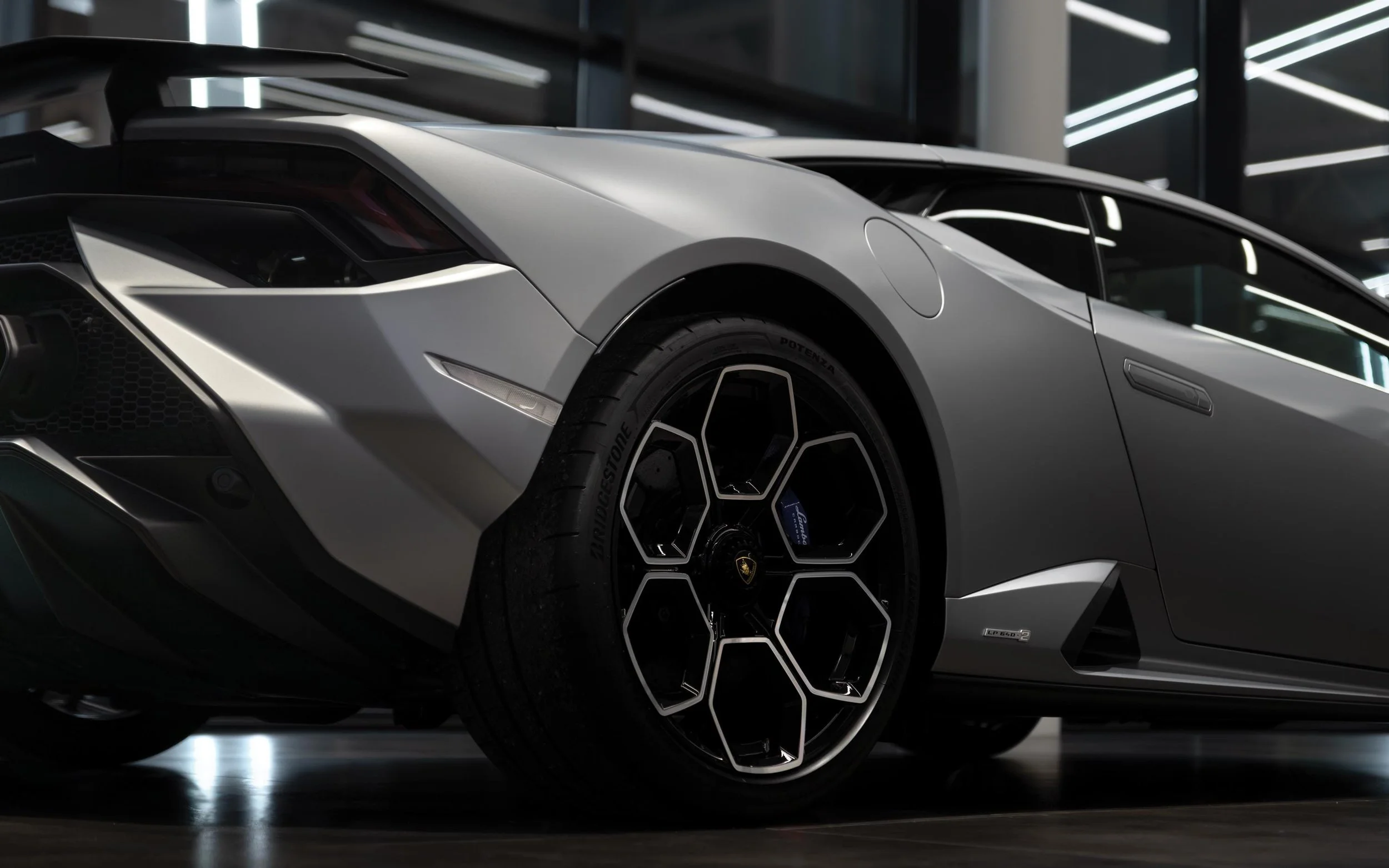Close-up of a sleek silver Lamborghini sports car showcasing the front and side view, with focus on the distinctive wheel and aerodynamic design.