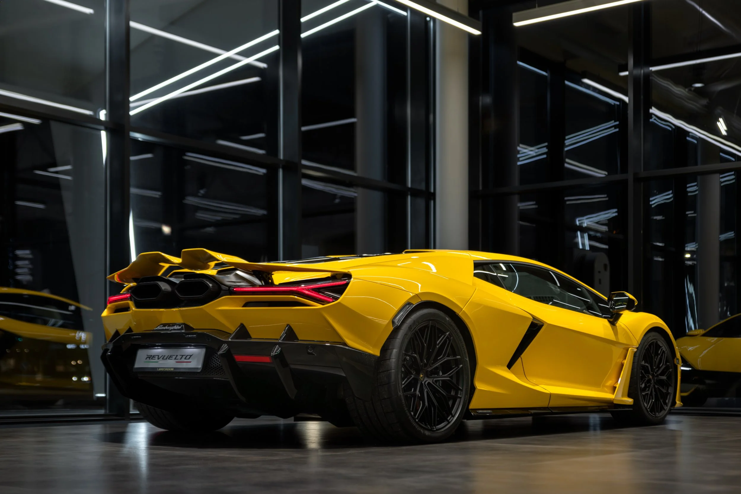 Yellow Lamborghini supercar inside a modern showroom with reflective glass and neon lighting.