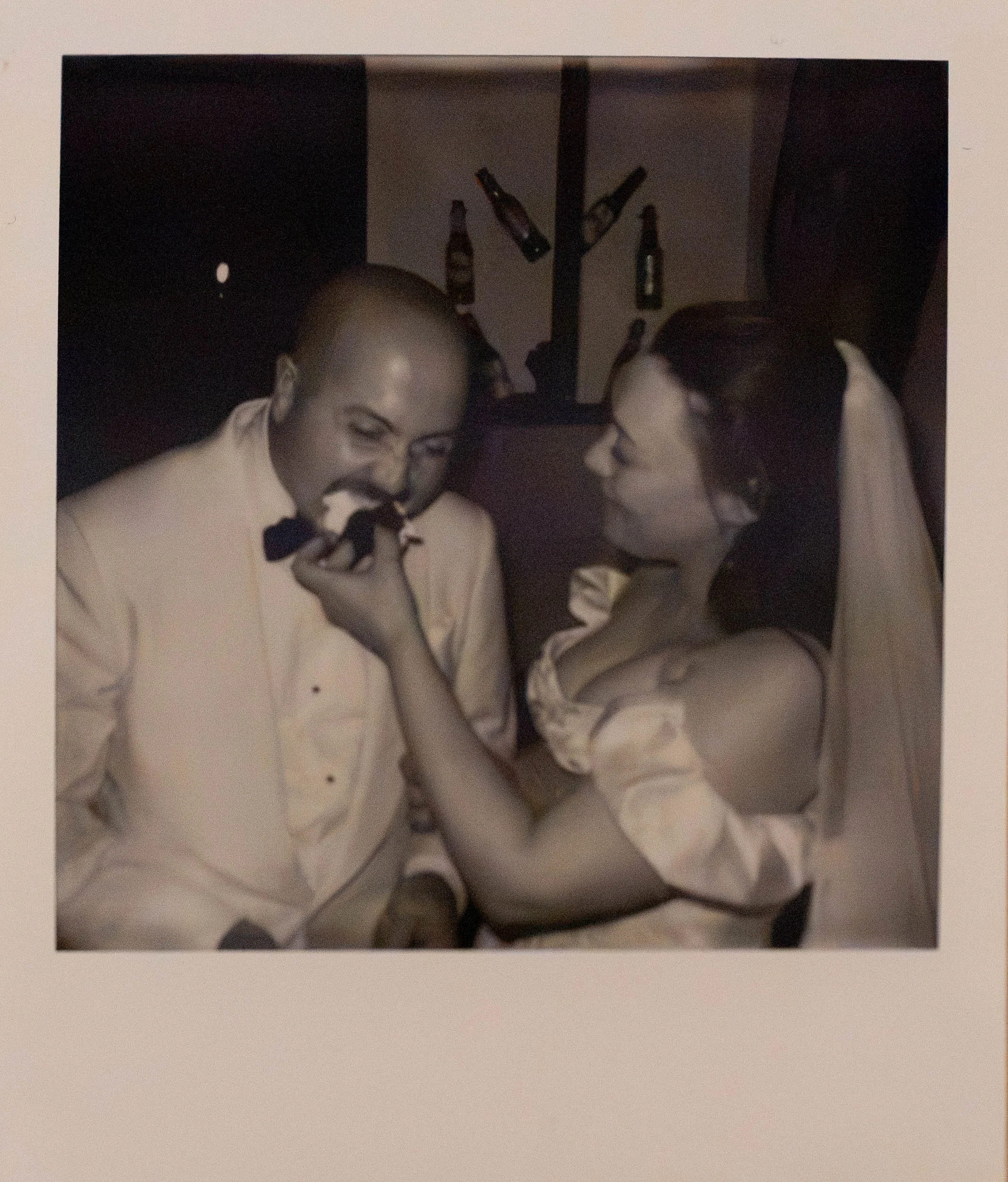 Polaroid of bride feeding groom cake