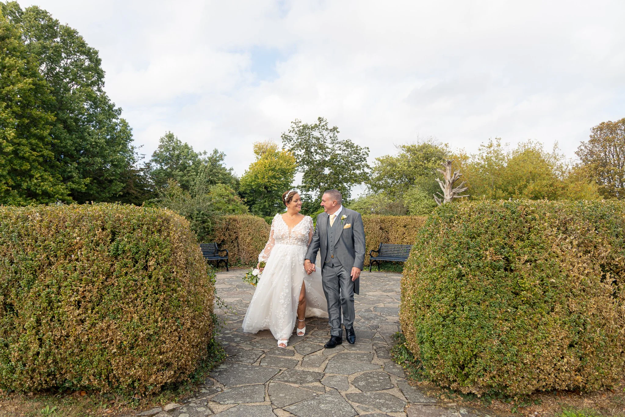 bride and groom smiling and walking through gardens