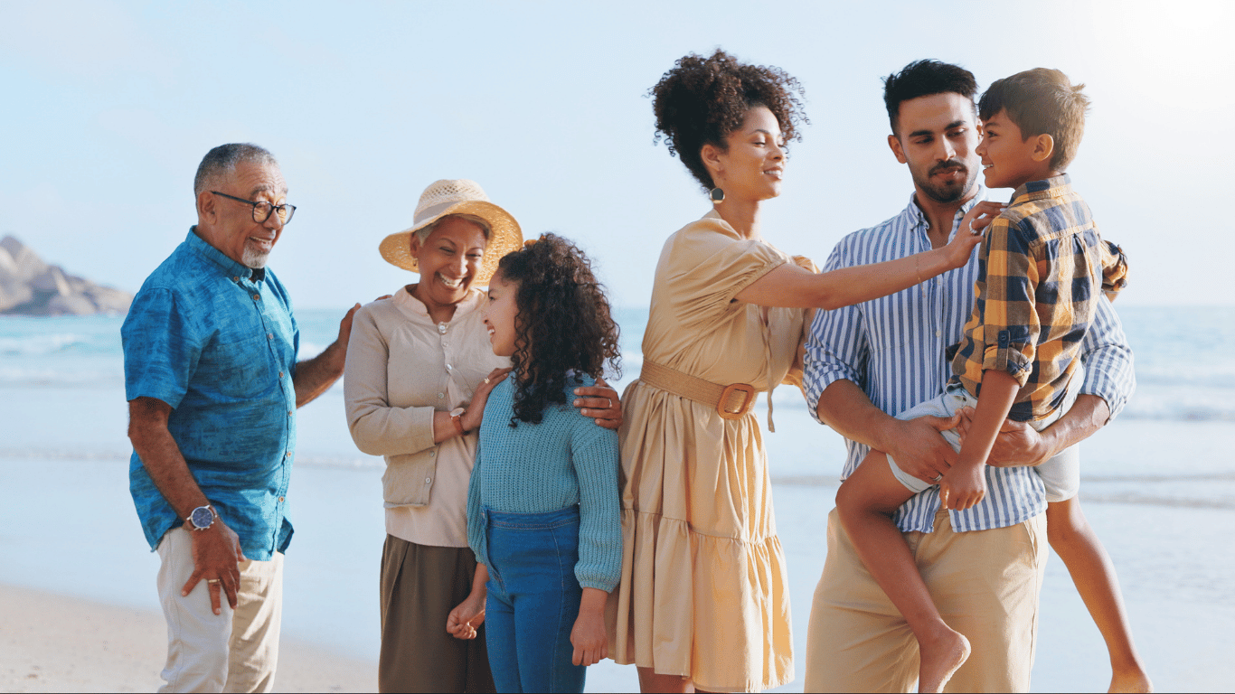 three generations of family laughing on the beach together