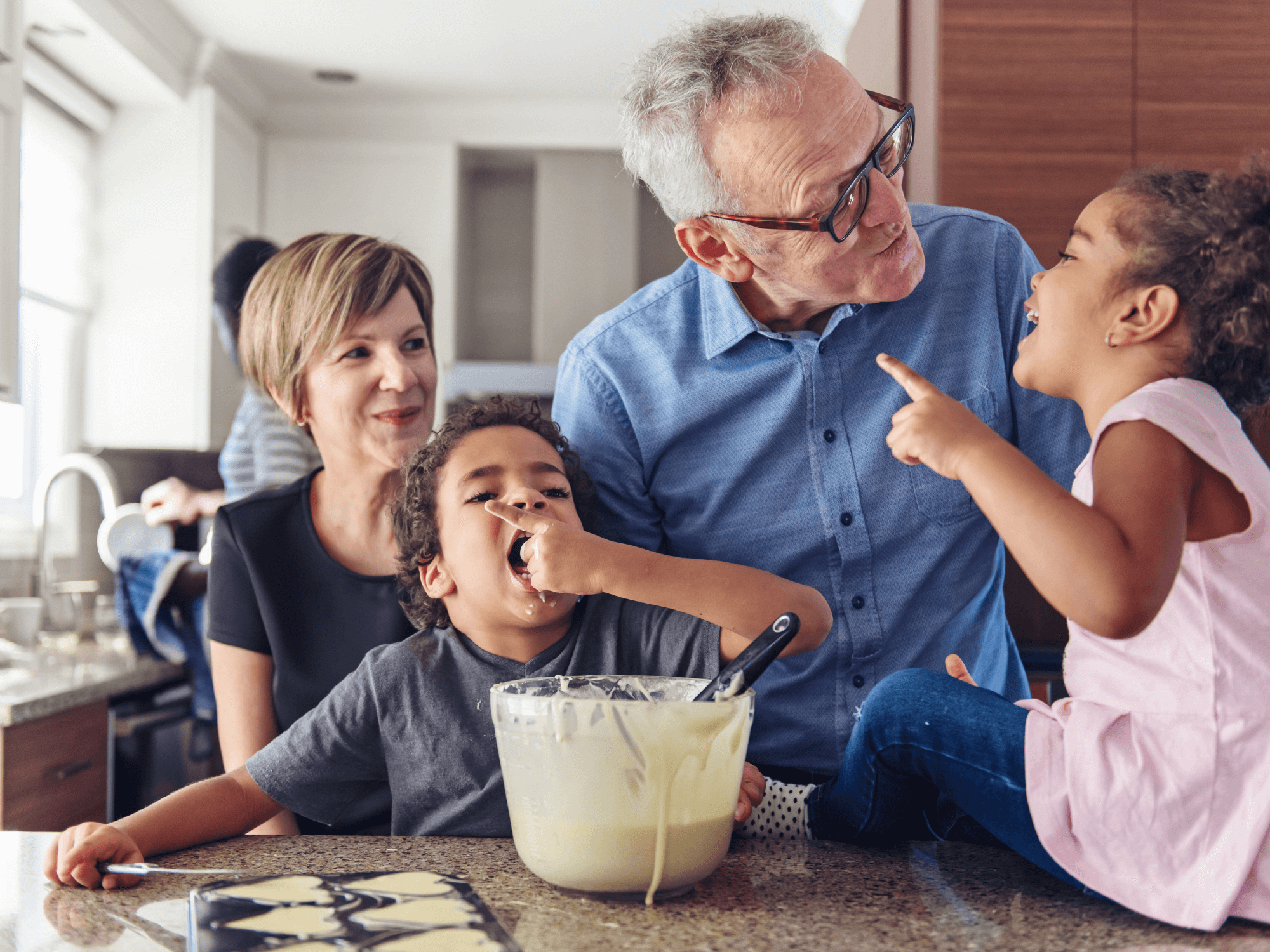 Grandparents and grandchildren baking together in the kitchen while mom washes dishes in the background