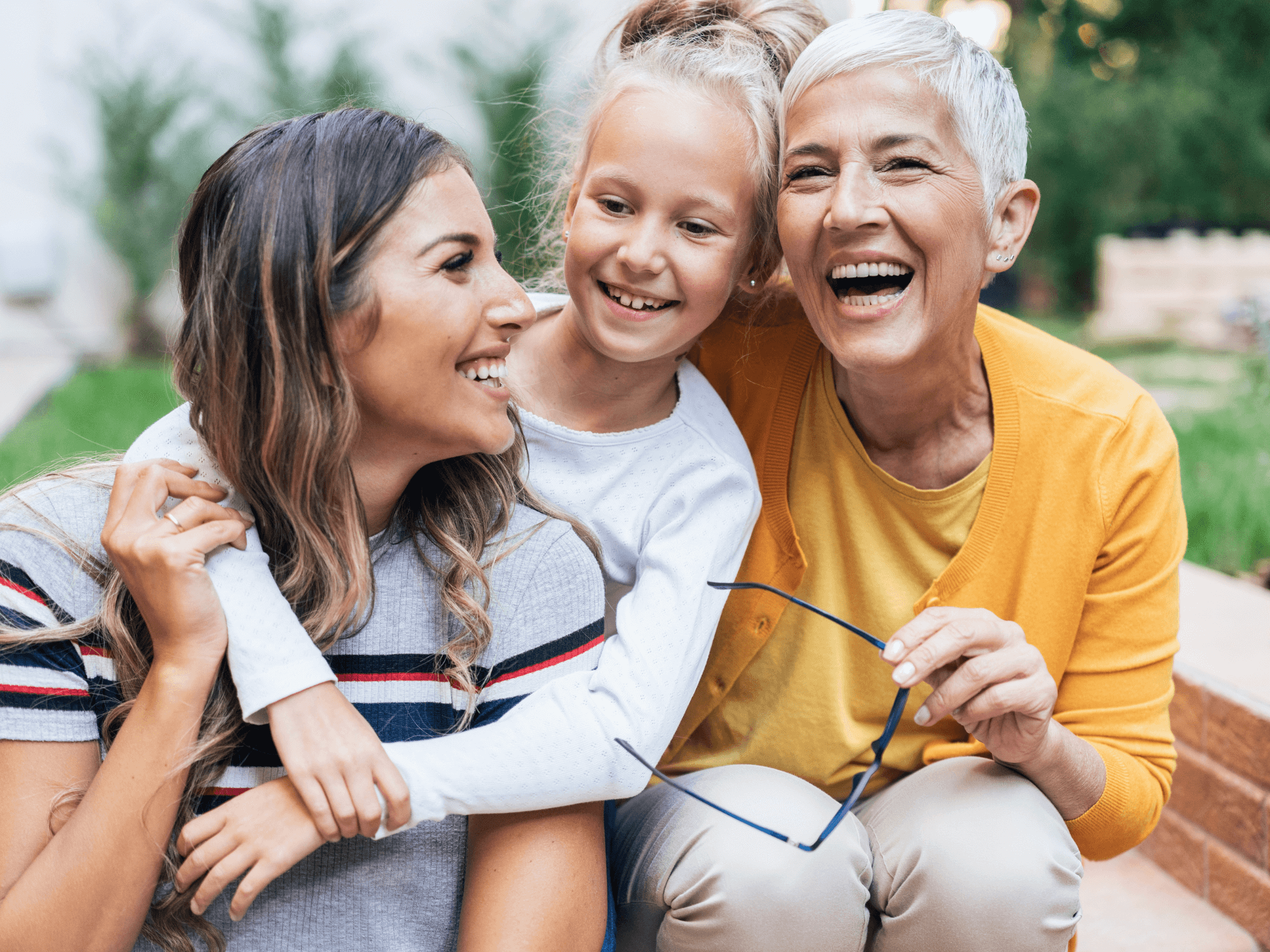 Mother, daughter and granddaughter laughing together outside