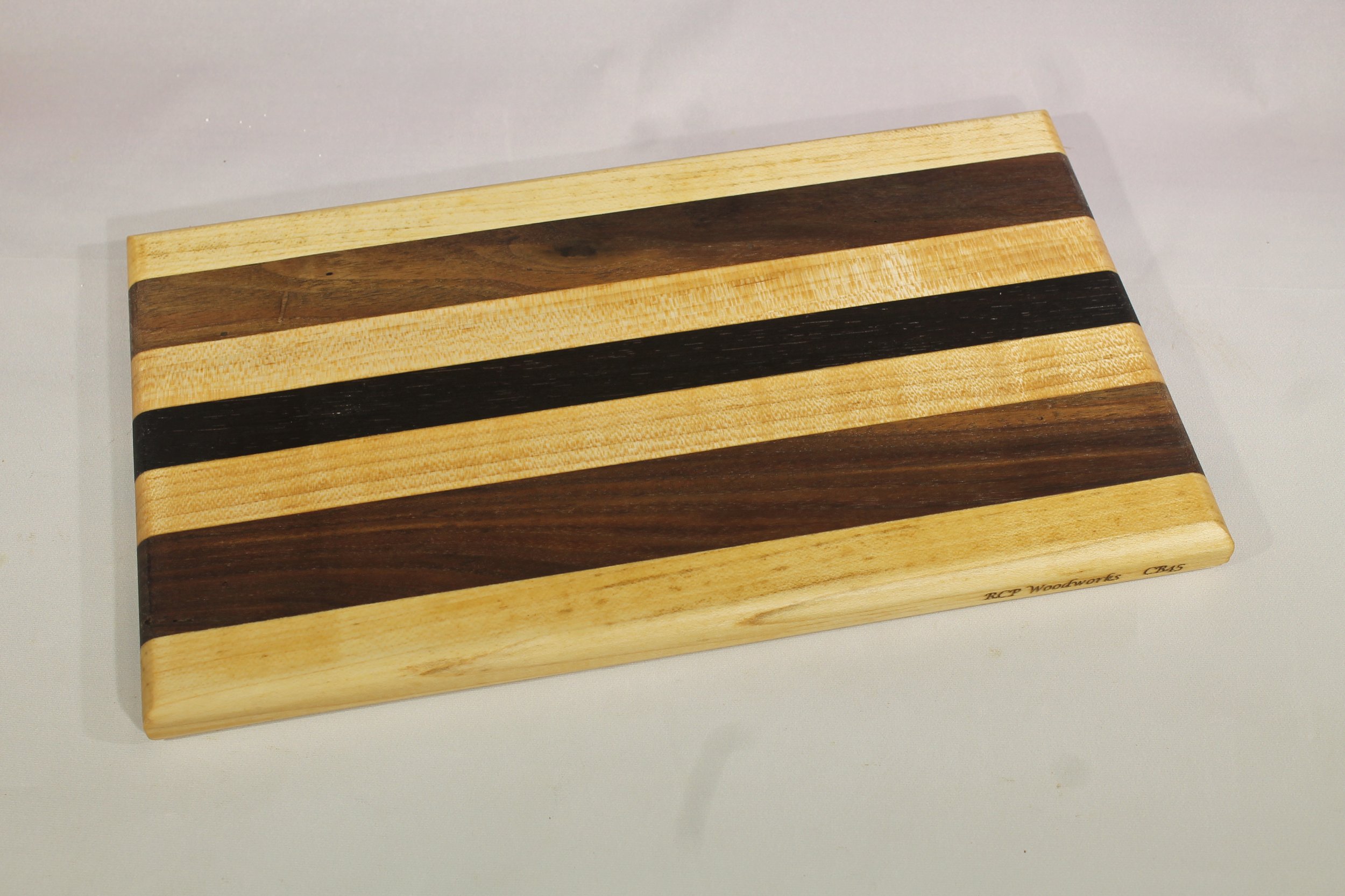 CB45A - Cheese & Cutting board.

6 1/8” wide by 10 ¾” long by 11/16” thick.
Seven segments of wood – Maple, Walnut, Maple, Wenge, Maple, Walnut, Maple.

Finished with cutting board oil.         $55
