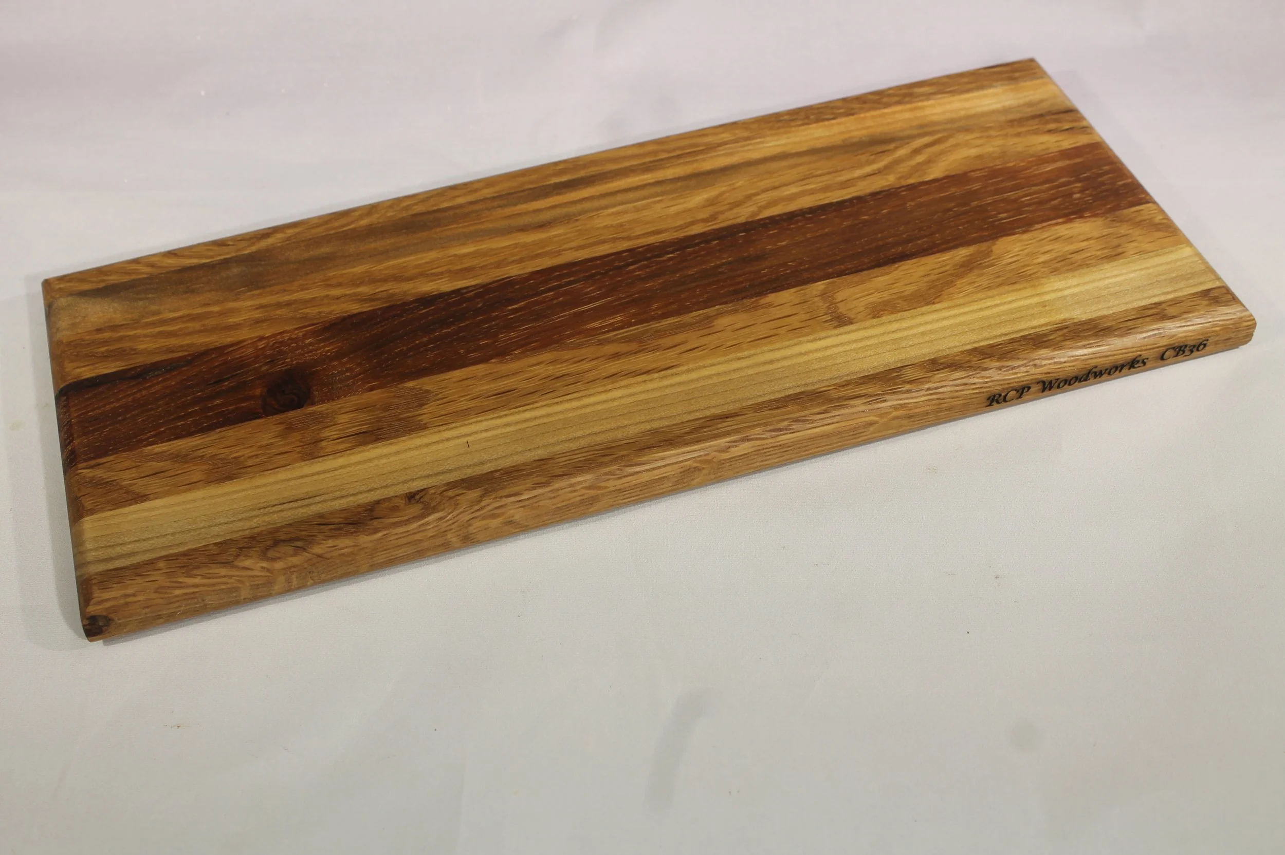 CB 36A - Cheese & Cutting board.

5 ¼” wide by 12 7/8” long by 5/8” thick.
Seven segments of wood – Oak, Maple, Oak, Cherry, Oak, Maple, Oak.

Finished with cutting board oil.         $50

