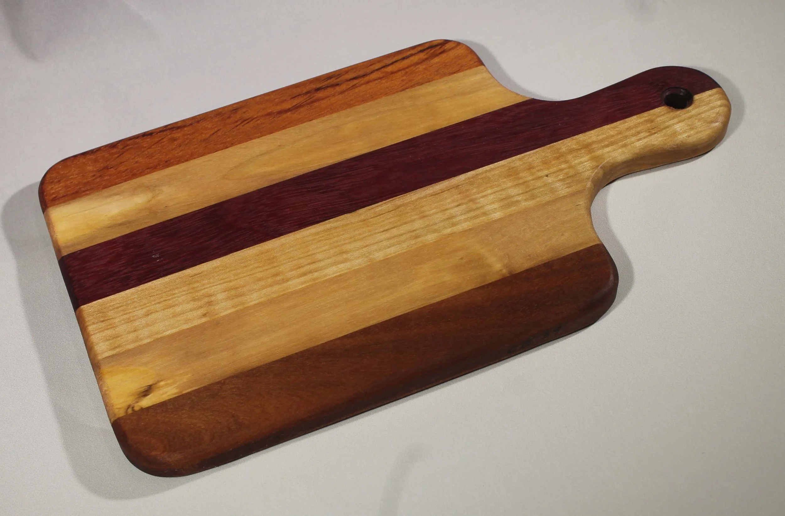 CB39  -  6” x 10 ¾” Cutting board with handle
                                                                      $35
	
6 segments – Walnut, Oak, Maple, Sapele, Oak, Bubinga
