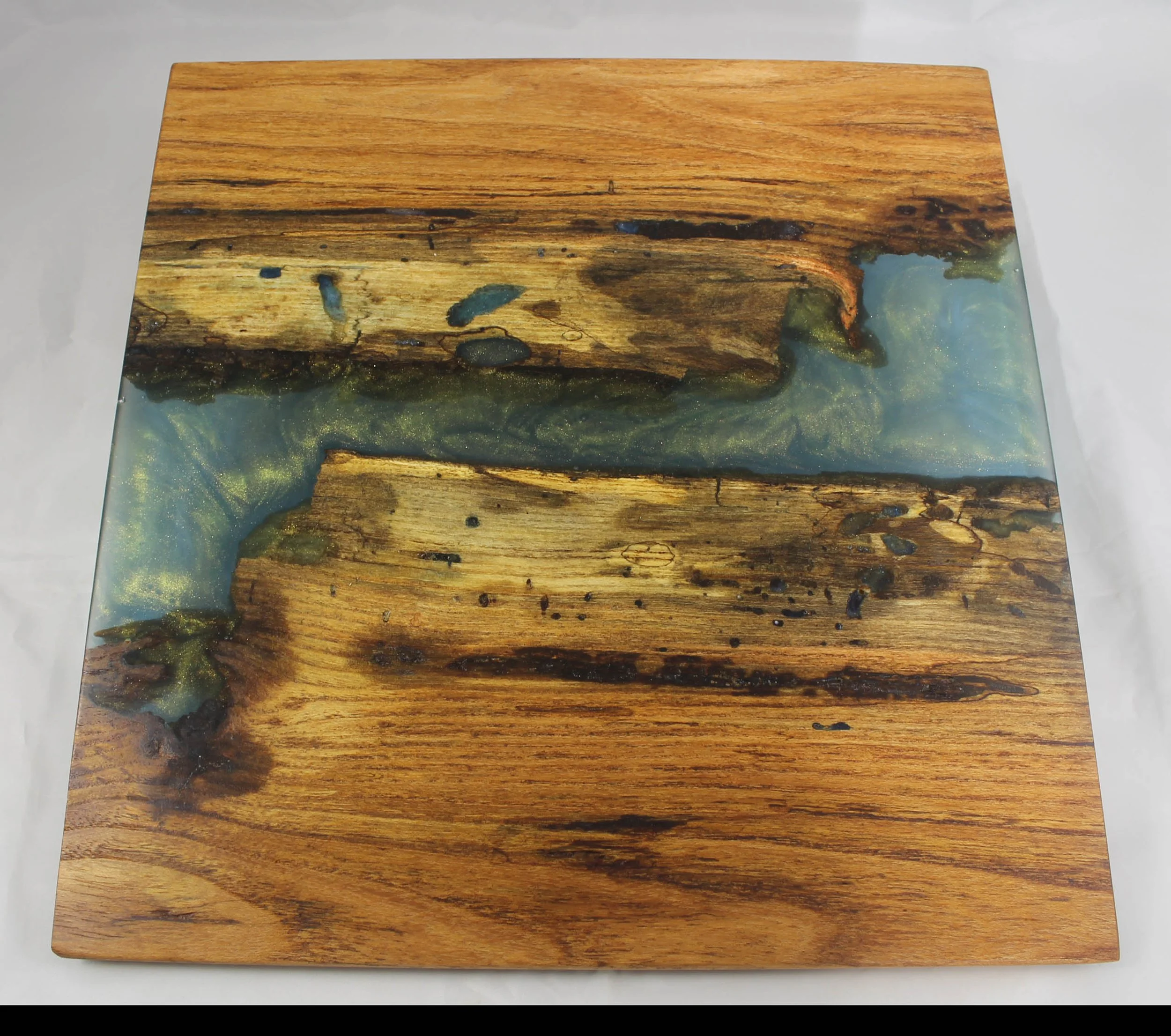 CB65 -  Charcuterie Board       

$200

This has honey locust wood with blue and gold mica powder epoxy resin.  It has a satin finish and is food safe.

This board is for serving cheese or other appetizers.  

It measures12” wide by 12 ½” long
Handwa
