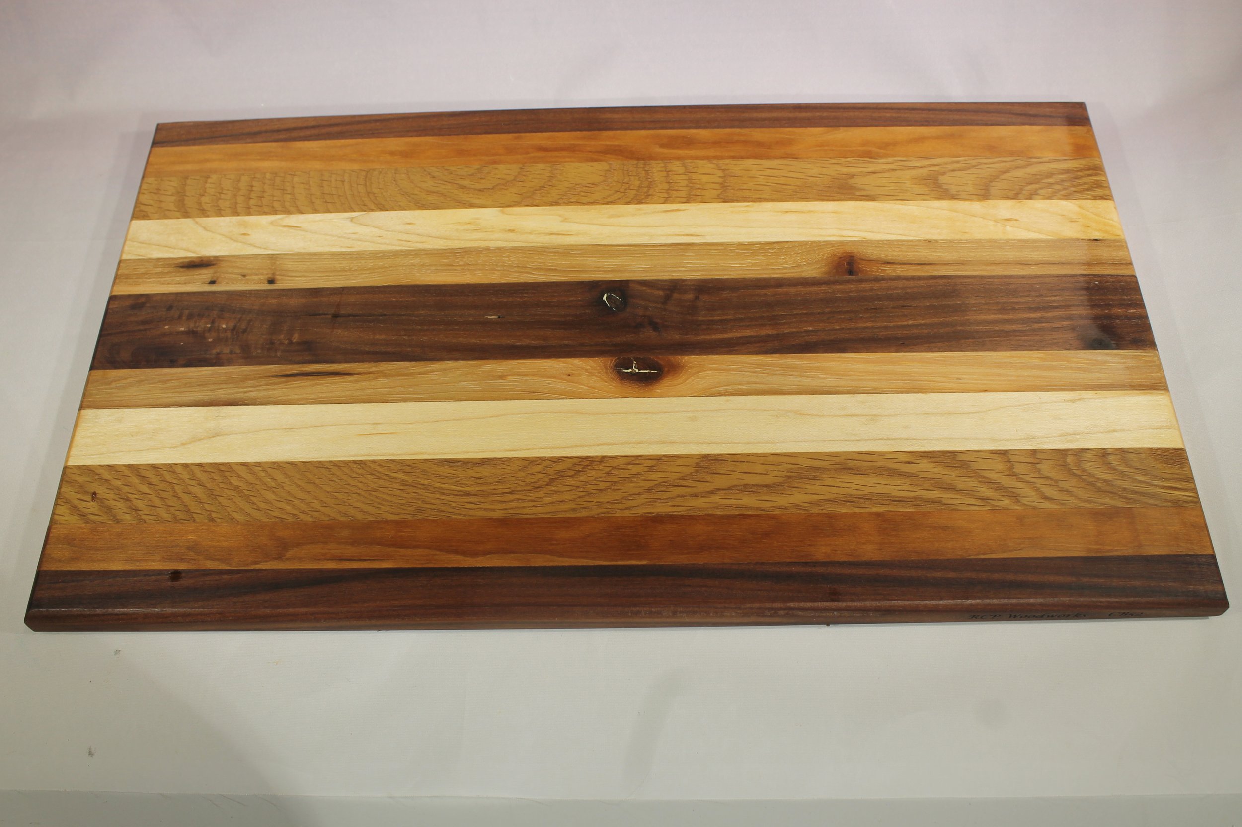 CB52  -   Charcuterie board          $80

10” wide by 17 ¼” long by 11/16” thick.
Eleven segments of wood – Walnut, Cherry, Oak, Maple, Pecan, Walnut, Pecan, Maple, Oak, Cherry, Walnut.

Finished with cutting board oil.
