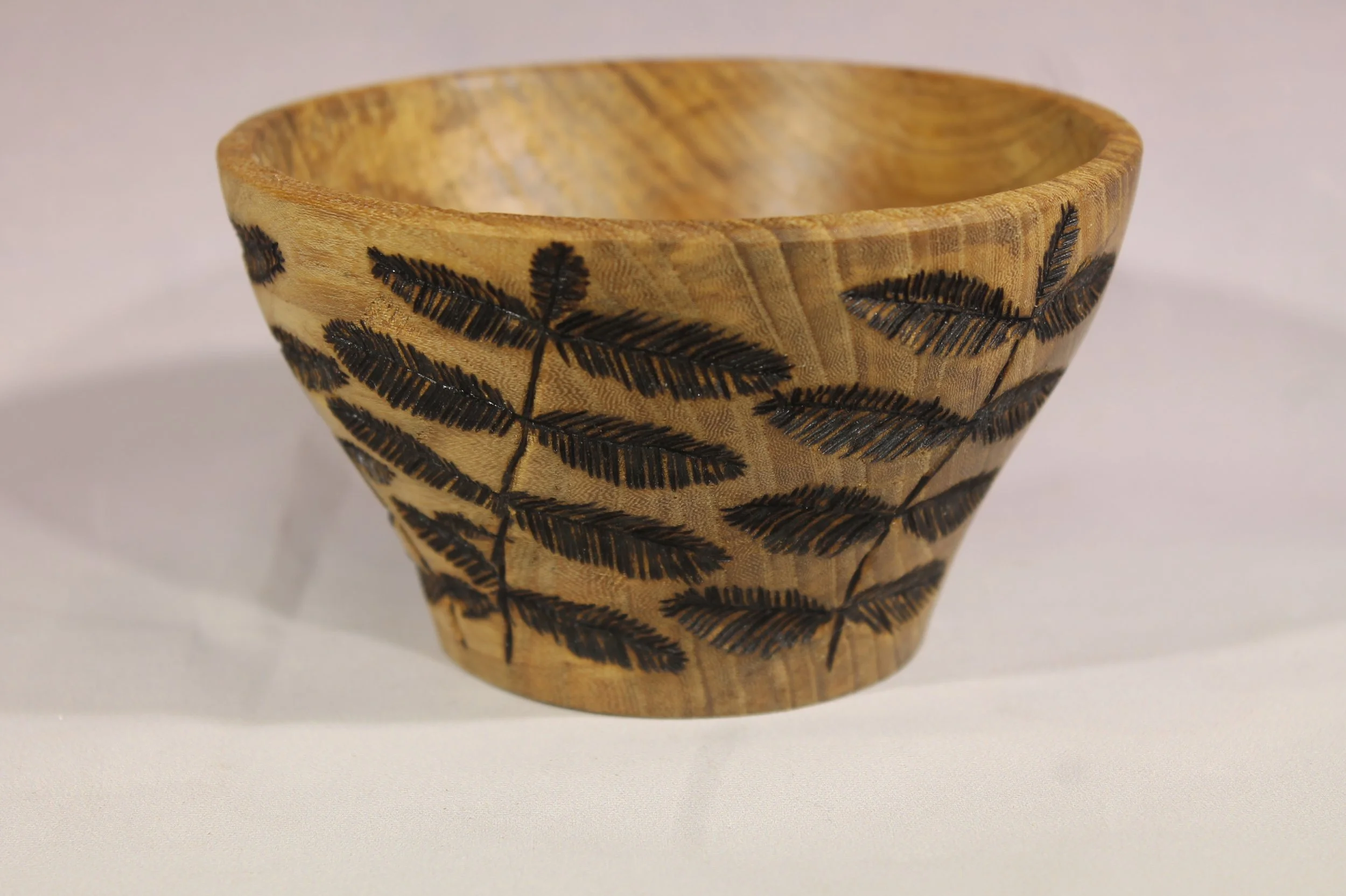 #6390 - Pecan bowl – embellished with a woodburned fern design. 
4 ¾”" diameter x 2 ¾” high.

Finished with Danish oil.                     $60
