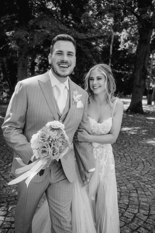 Ein glückliches Brautpaar auf einer Hochzeit im Grünen, schwarz-weiß Foto.