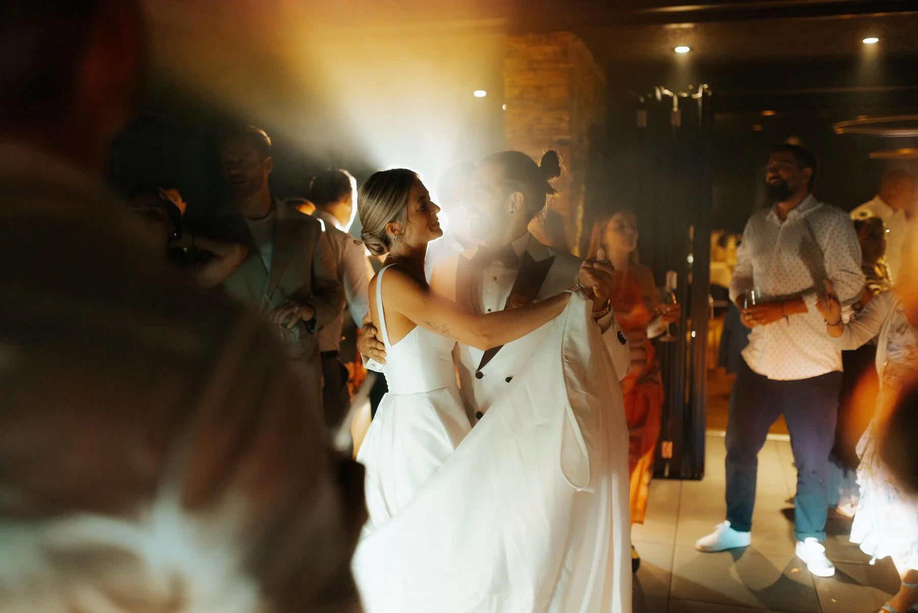 Paar, vermutlich Braut und Bräutigam, tanzt auf einer Hochzeitsfeier im Kerzenlicht, umgeben von Gästen.
