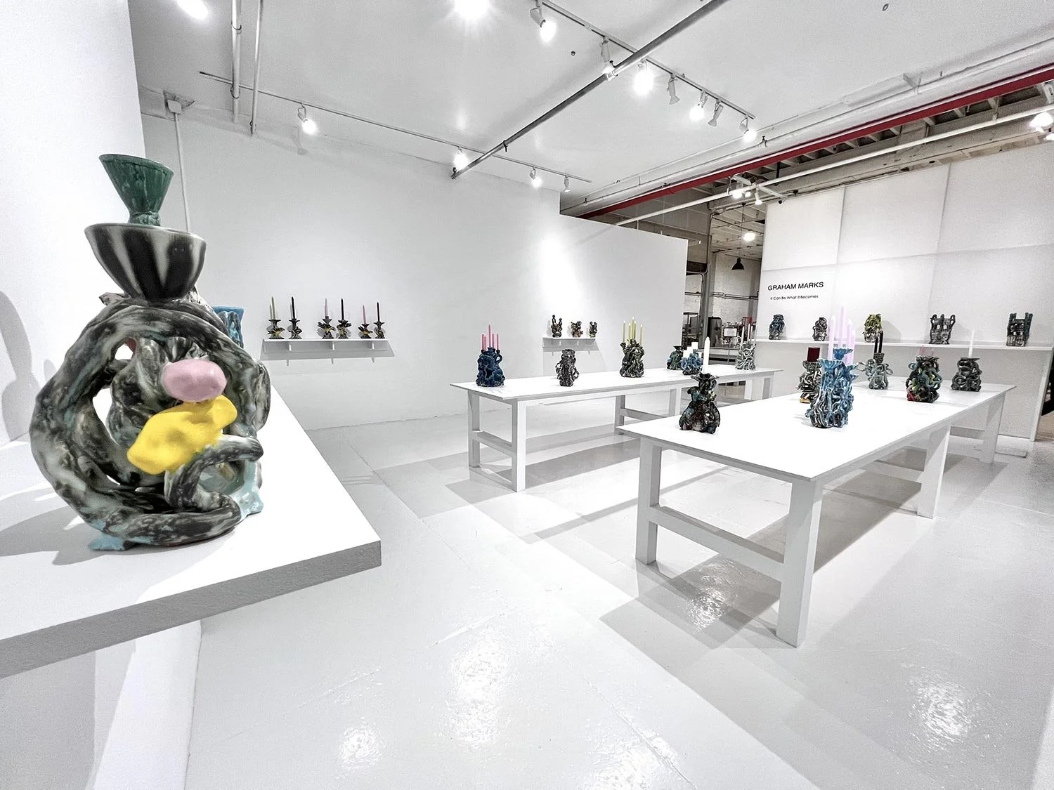 SSNYC Art gallery with abstract sculptures displayed on white tables and shelves; predominantly white walls and floors with modern lighting.
