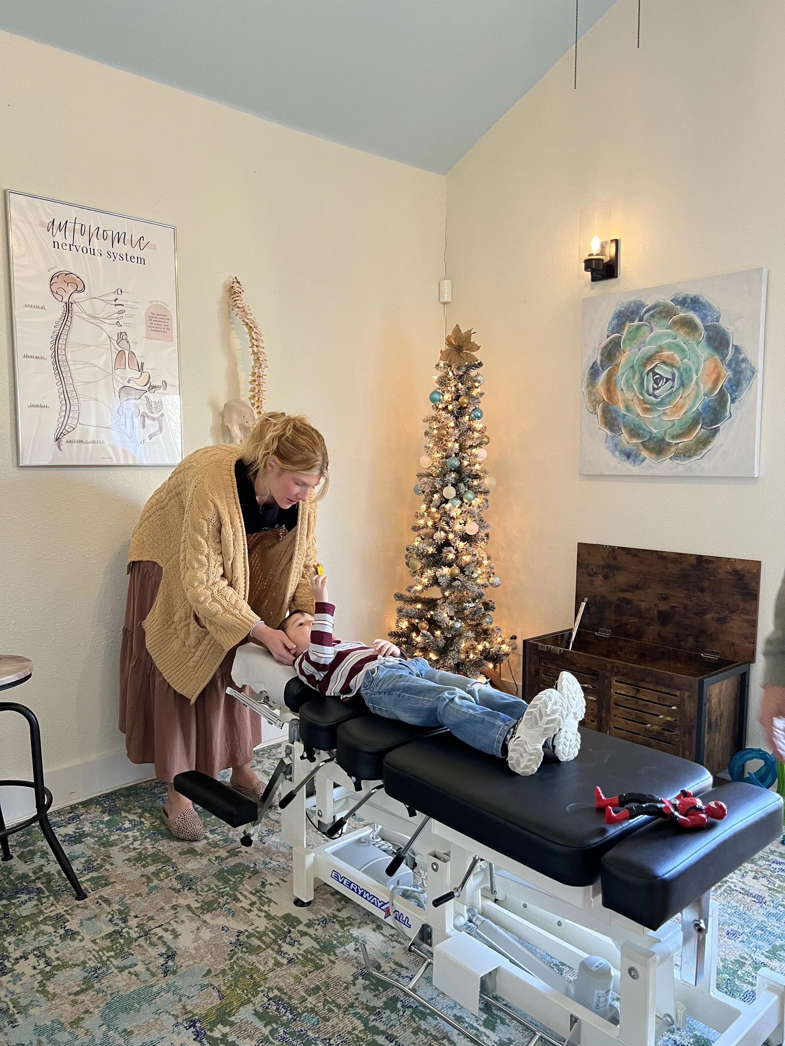 Dr Jessica Faulkenberry adjusting a child on chiropractic table at The Chiropractic Place for Mommy and Me in Aledo, Texas