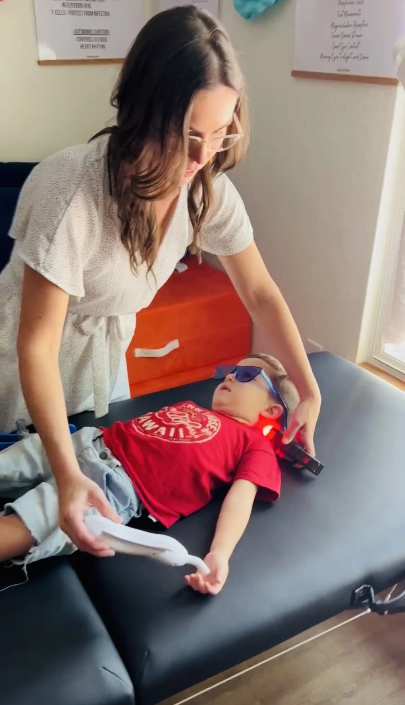 Dr Michelle using color, cold laser, rezzimax with vagus nerve frequencies to help with primitive reflex integration at The Chiropractic Place for Mommy and Me in Aledo, Texas at his childhood development chiropractic visit