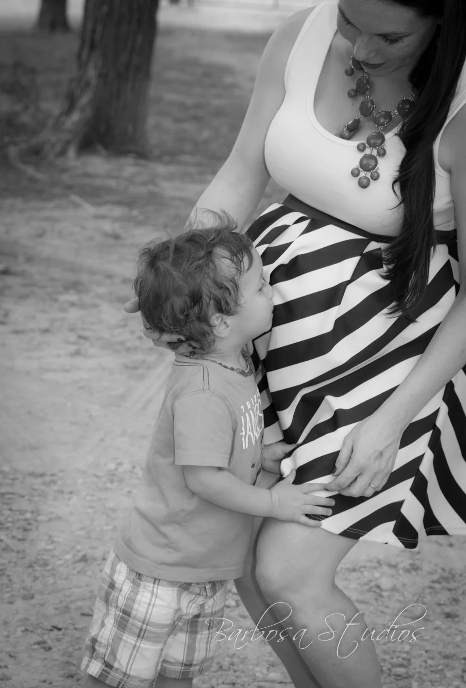Child kissing the belly of pregnant mother at The Chiropractic Place for Mommy and Me in Aledo, Texas