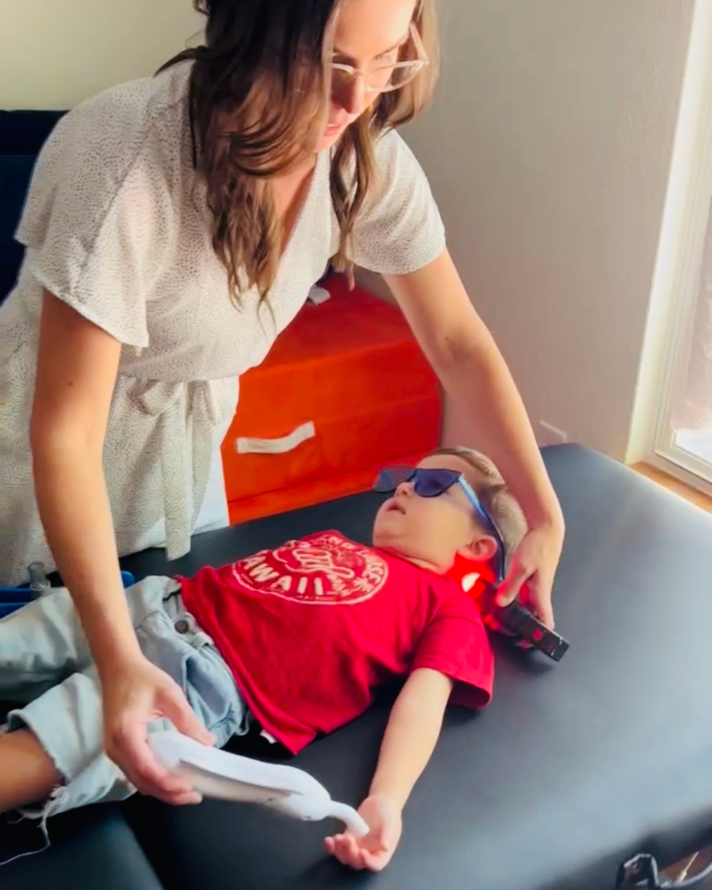 Dr Michelle Parker working on child for childhood development using rezzimax and cold laser for sensory and primitive reflex integration