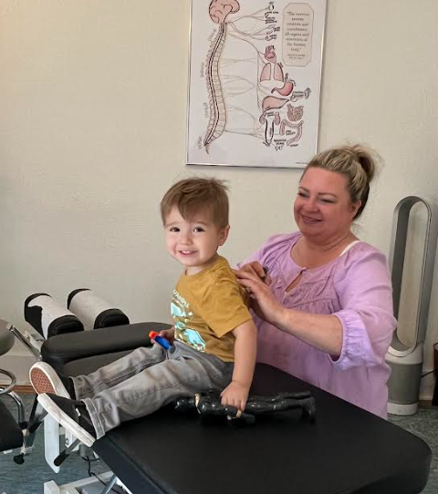 Dr Leslie Hasbini using an activator to perform a pediatric chiropractic adjustment on a child at The Chiropractic Place for Mommy and Me in Aledo, Texas