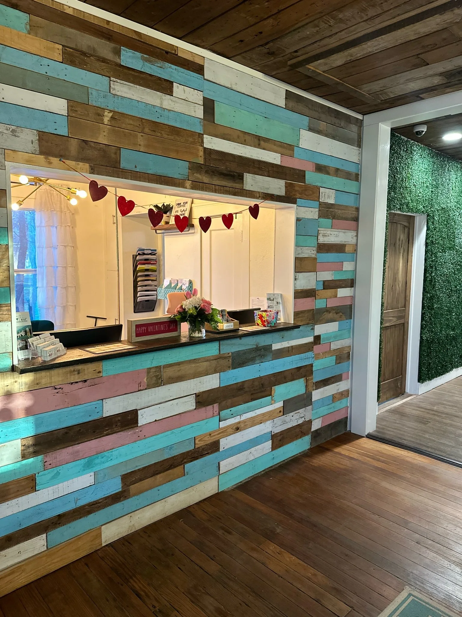 Picture of reception desk at The Chiropractic Place for Mommy & Me in Aledo, Texas with the colorful pallet wood that they are iconic for and where they greet new prenatal, pediatric and family chiropractic and massage families