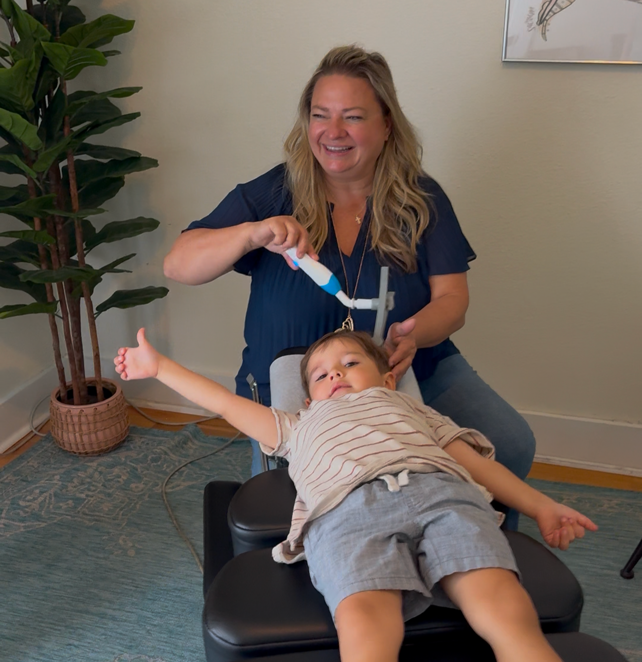 Dr Leslie Hasbini using the rezzimax vagus nerve support tool on a child in her pediatric chiropractic office at The Chiropractic Place for Mommy & Me in Aledo, Texas