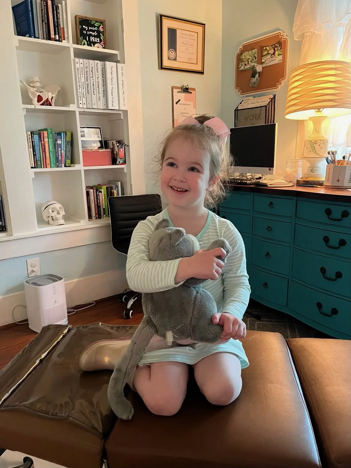 Young child sitting on chiropractic table in The Chiropractic Place for Mommy & Me in Aledo, Texas smiling