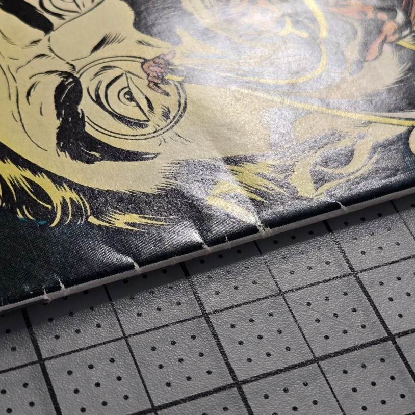 Close-up of a comic book spine under raking light revealing non-color-breaking defects that professional CGC pressing can fix
