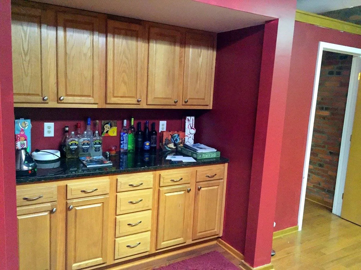 Kitchen bar area with wooden cabinets, bottles of alcohol, and a countertop.