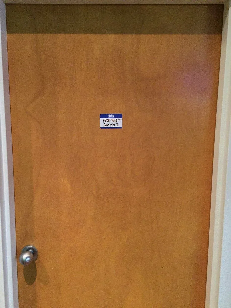 A wooden door with a small Hello my sticker that says 'For Rent' and 'Ask Me J' in the middle.