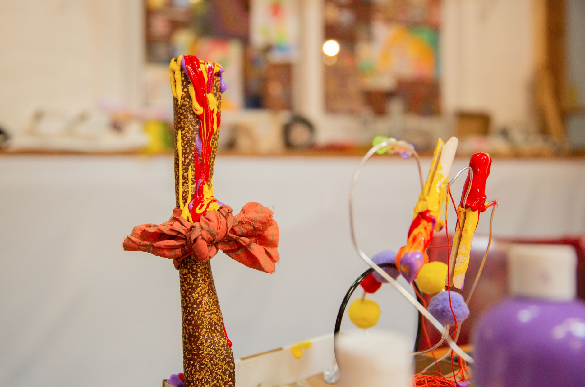Colorful abstract art sculpture with various materials, including red, yellow, and purple paint, fabric, and wire.