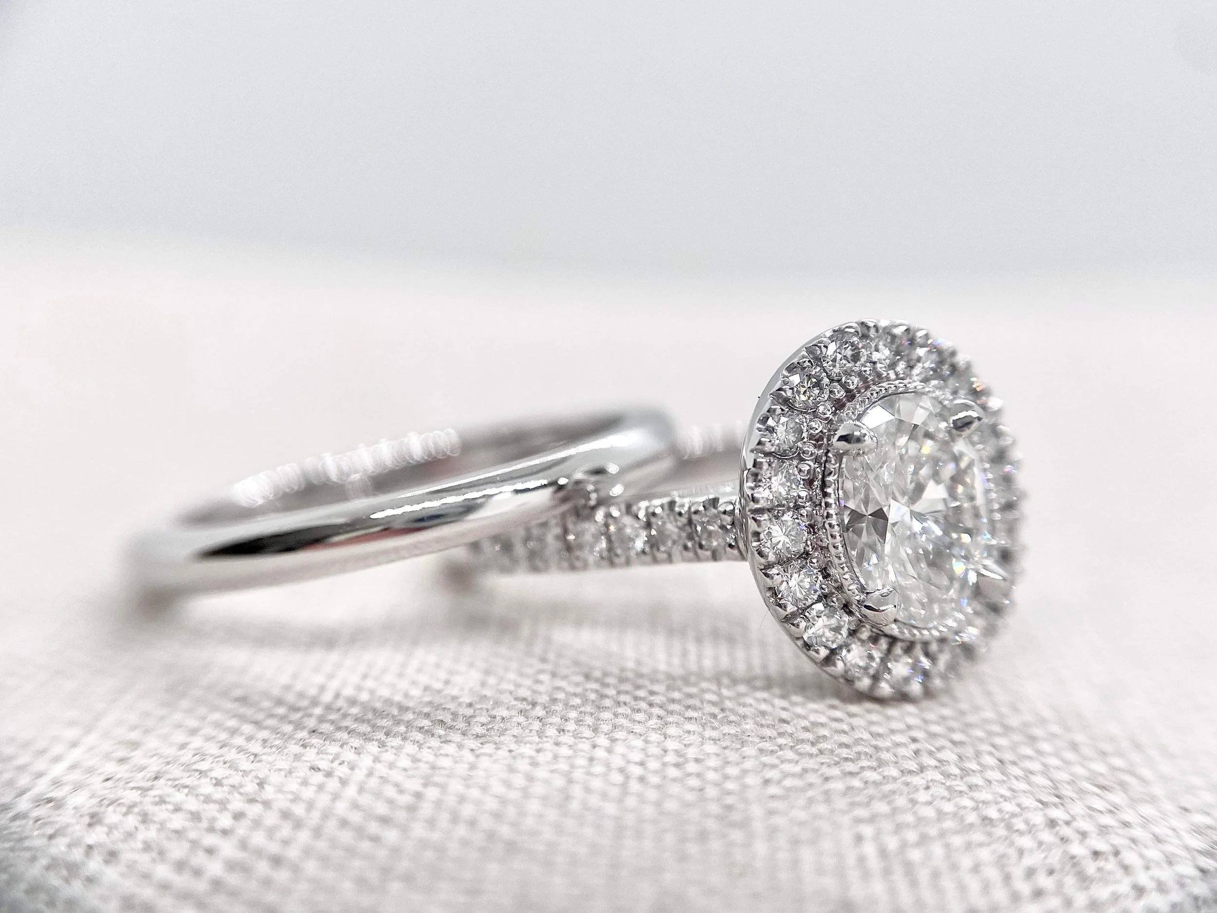 18ct white gold engagement ring, oval centre stone, milgrain setting. Straight half round wedder.