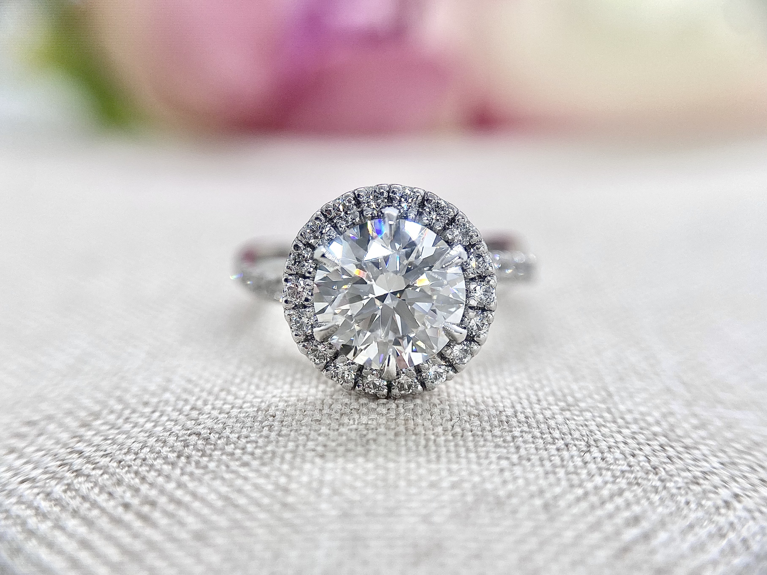 18ct white gold ring featuring a 1.84ct round brilliant cut diamond and diamond halo, sitting on a rope twisted diamond set band.