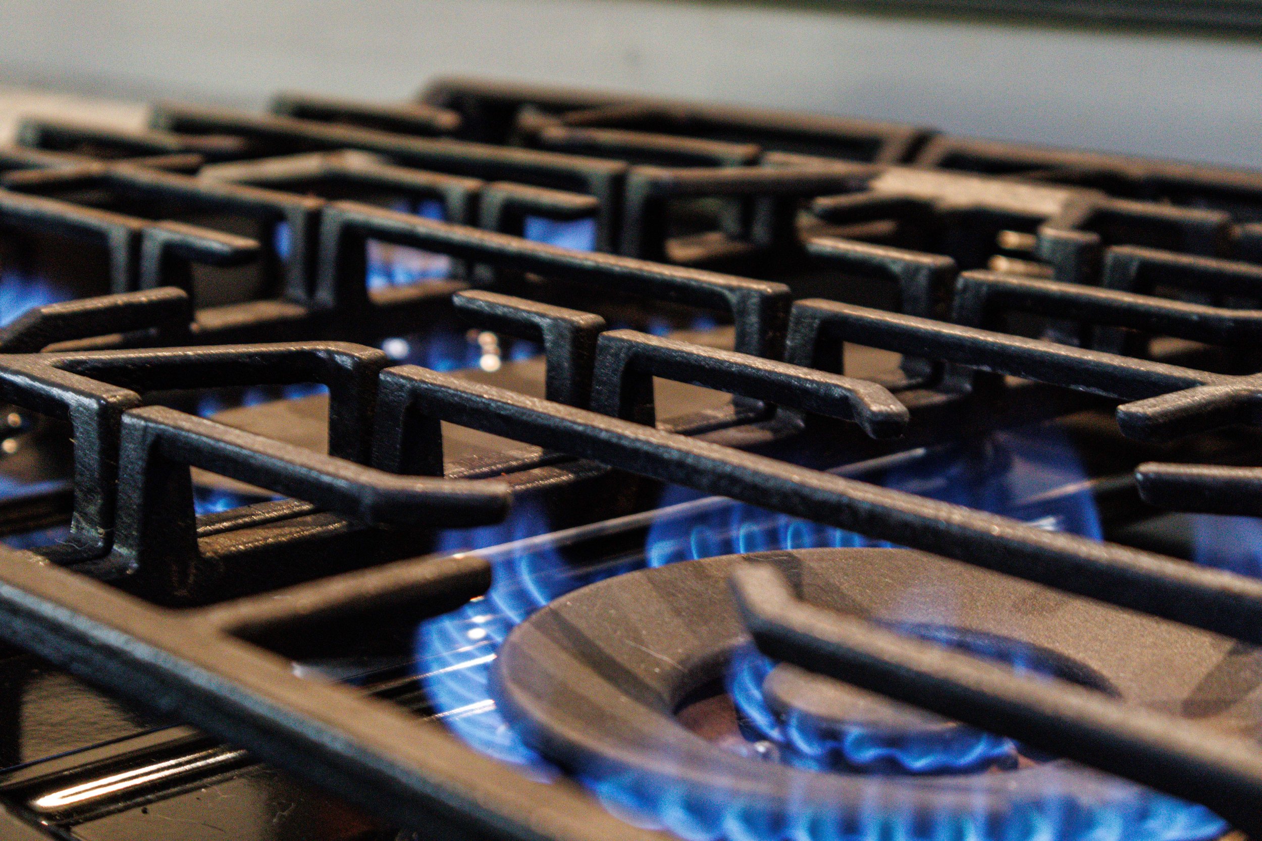 Close-up of a lit gas stove burner with blue flames and cast iron grates.