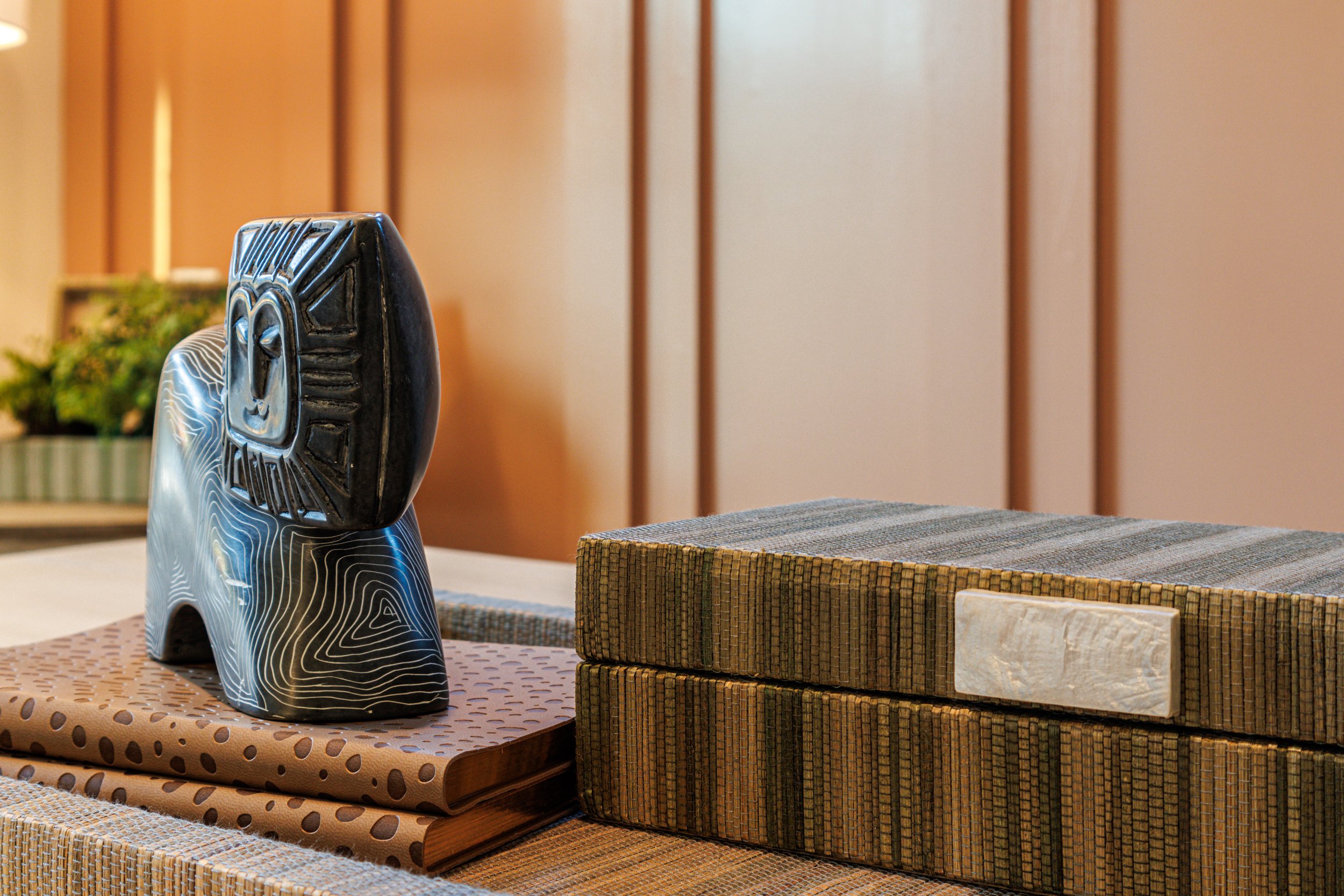 Decorative ceramic cat sculpture on patterned books with wooden wall background