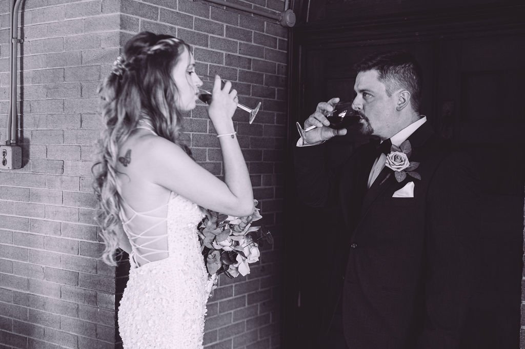 A bride and groom sharing a celebratory drink of wine after their wedding ceremony at Searles Chapel in Windham, NH. Wedding photography by Mike Indi.