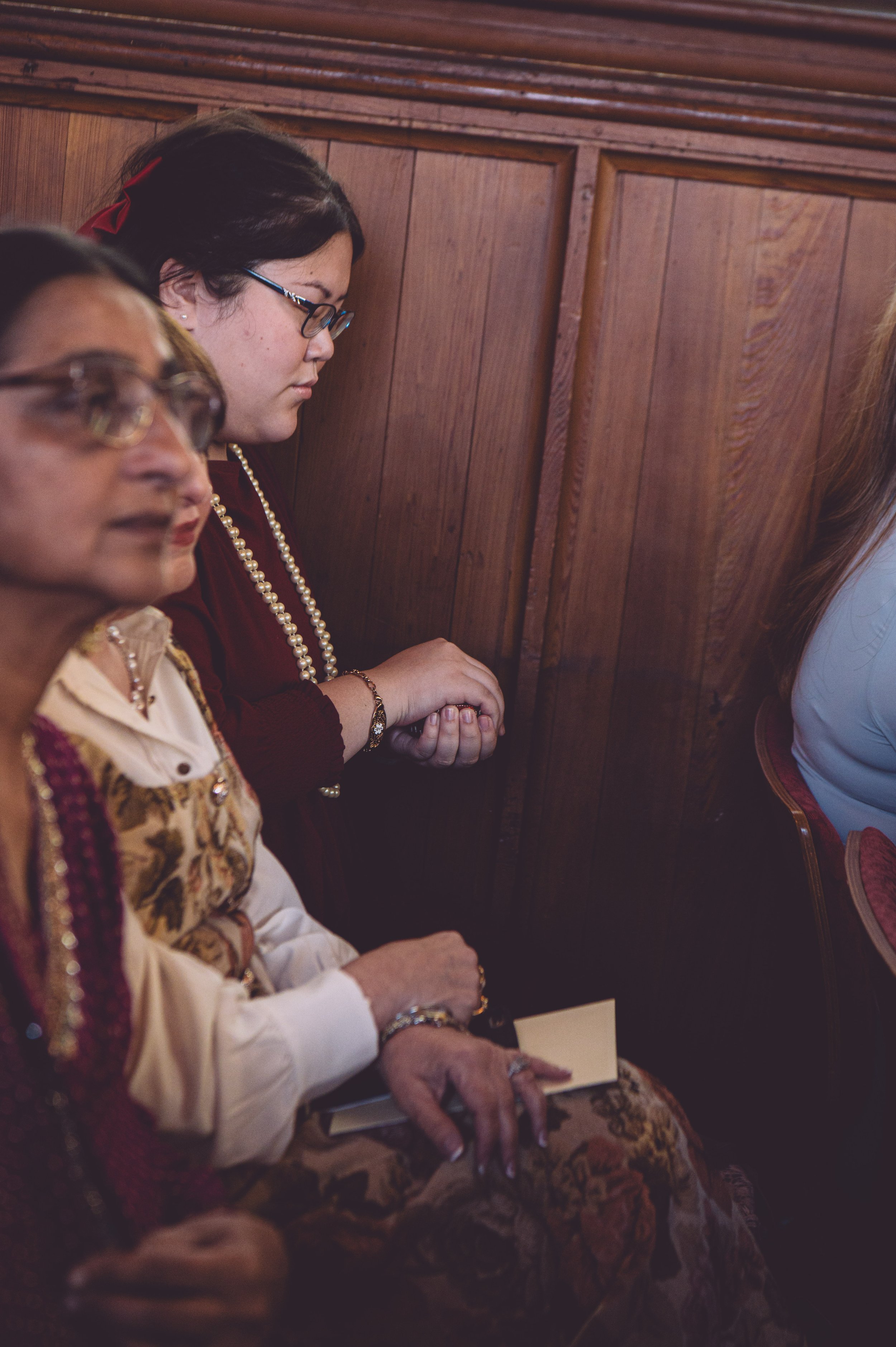 A wedding guest holding a wedding ring box and passing love and blessings to the couple during their wedding ceremony at Searles Chapel in Windham, NH. Wedding photography by Mike Indi.