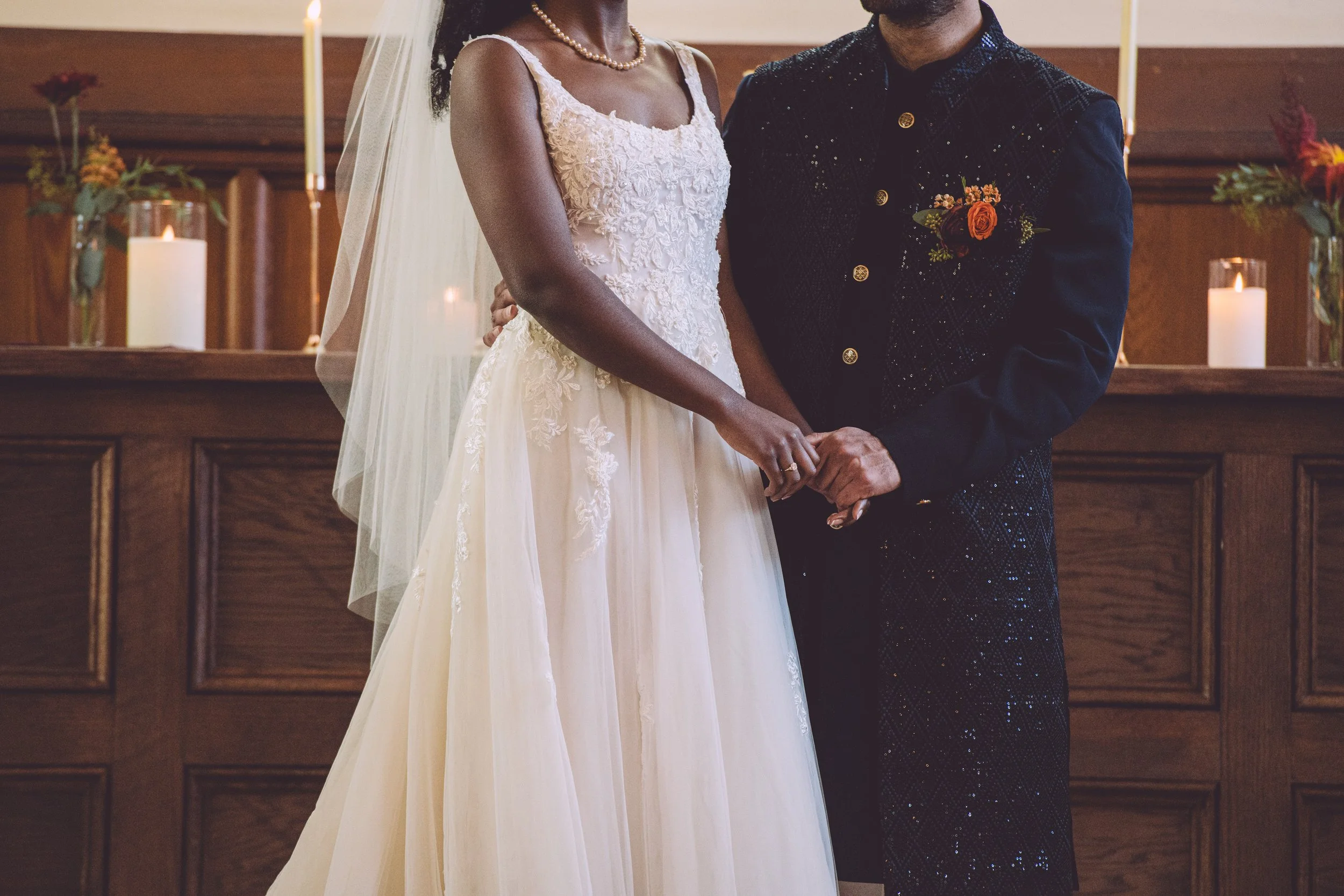 A bride and groom holding hands during their wedding ceremony at Searles Chapel in Windham, NH. Wedding photography by Mike Indi.