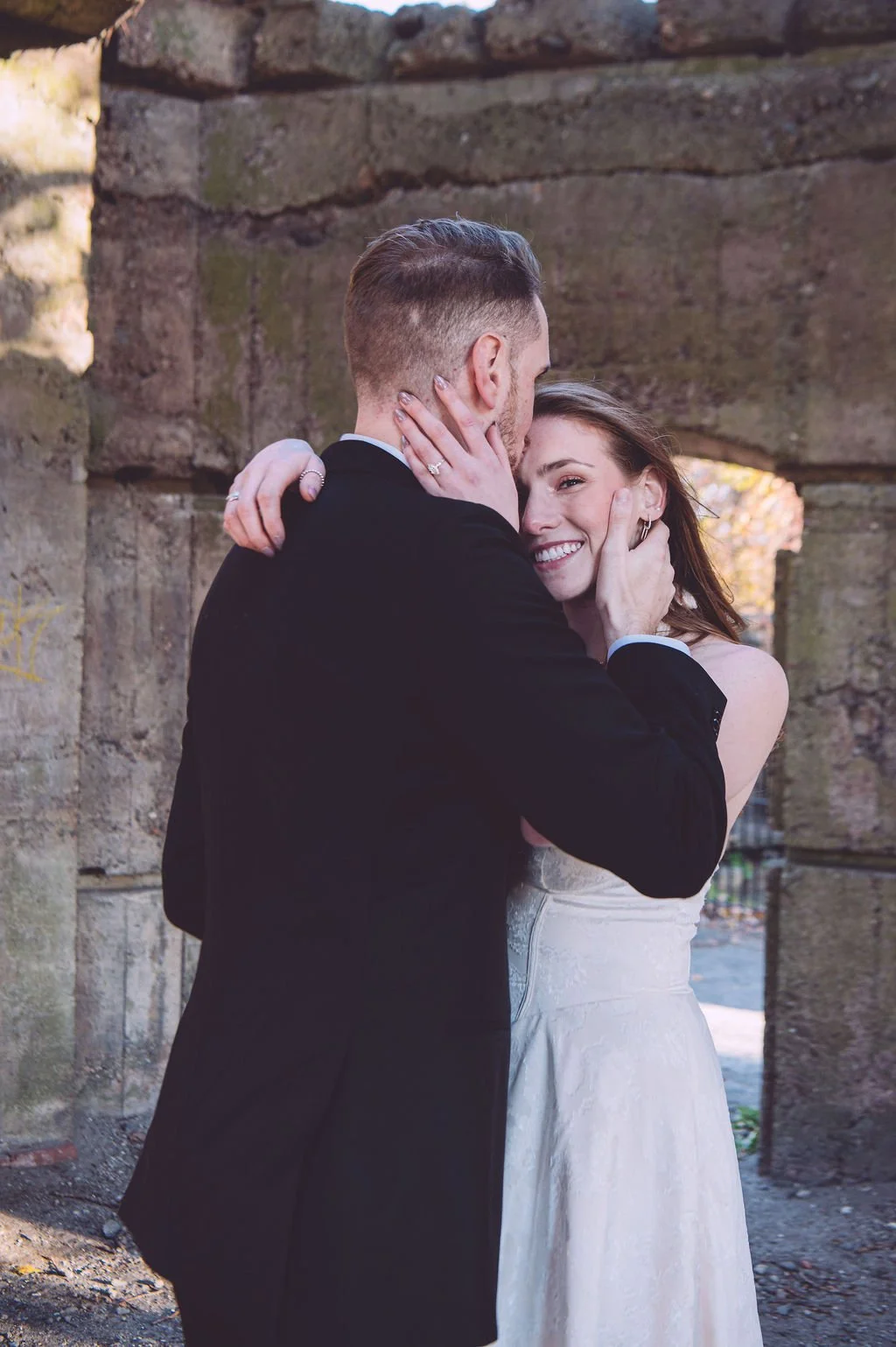 A groom kissing the top of his bride's head during a tender moment during their engagement session at Bancroft's Castle in Windham, NH. Engagement photography by Mike Indi.