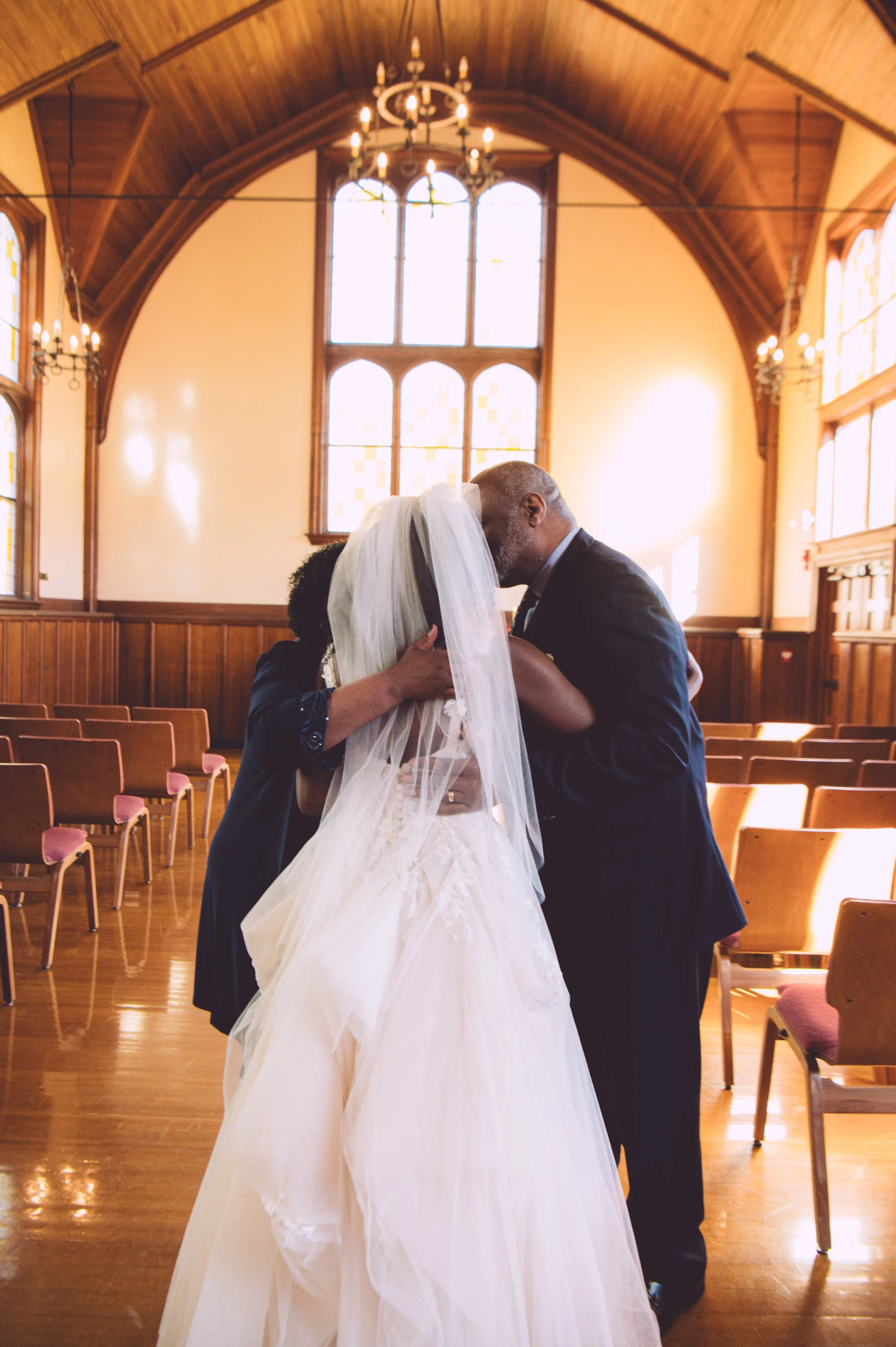 A bride sharing a loving moment with her parents before her wedding at Searles Chapel in Windham, NH. Wedding photography by Mike Indi.