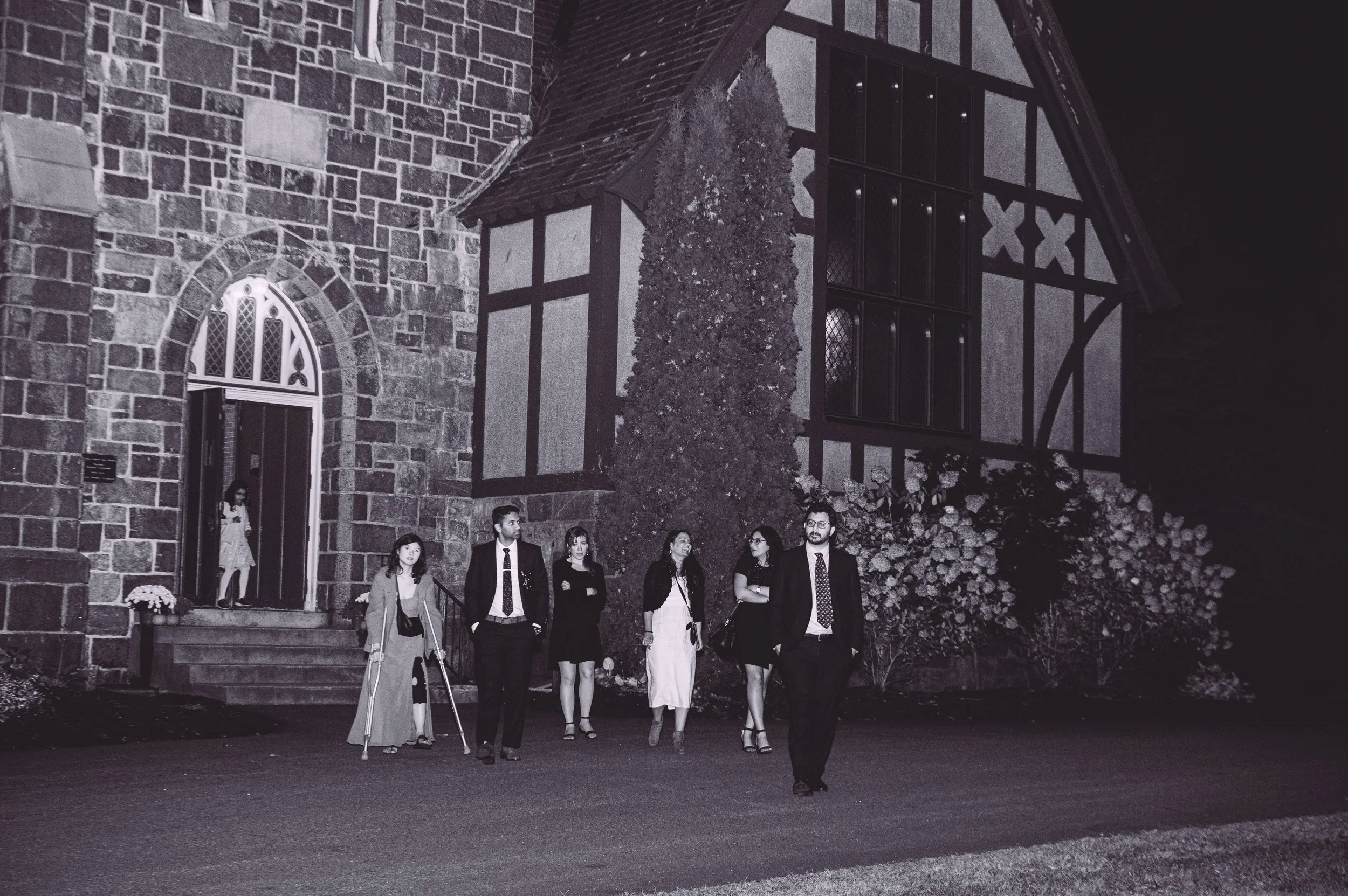 Wedding guests walking towards the bride and groom out front of Searles Chapel during their fall wedding. Wedding photography by Mike Indi.