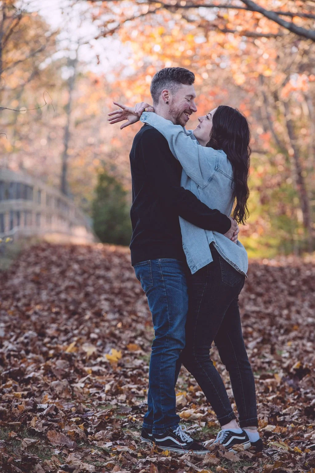 Sarah and Alex laughing and embracing among fall foliage during an engagement session in Portsmouth, New Hampshire - photography by Mike Indi