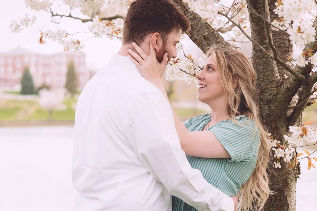 Hannah and Ben sharing an intimate moment under a blooming tree during their spring engagement session in downtown Portsmouth, NH. Photography by Mike Indi.