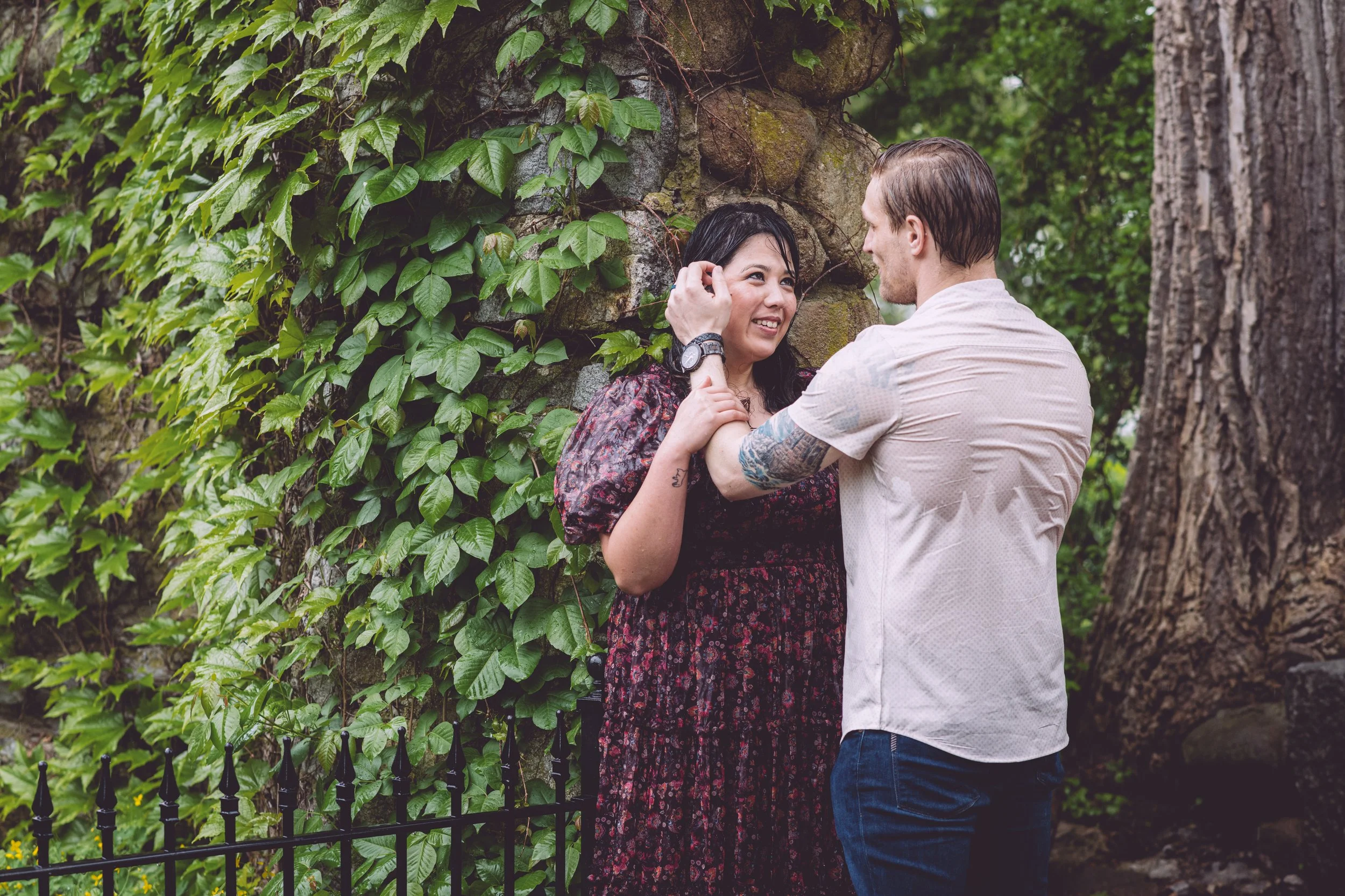 A couple soaked from the rain in a romantic embrace during their engagement session at Bancroft's Castle in Groton, MA. Engagement photography by Mike Indi.