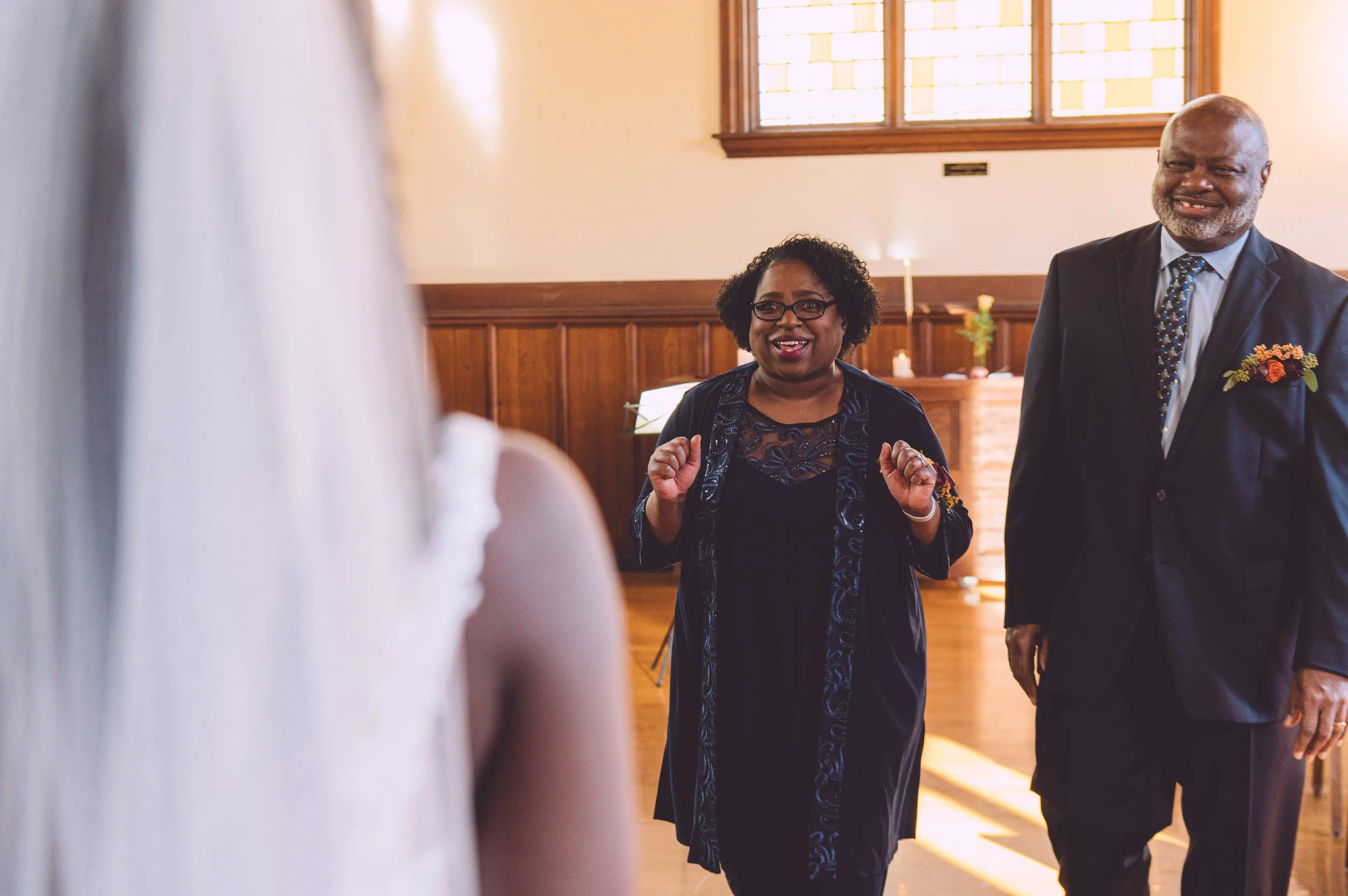 A bride approaching her parents to share a first look with them before her wedding at Searles Chapel in Windham, NH. Wedding photography by Mike Indi.