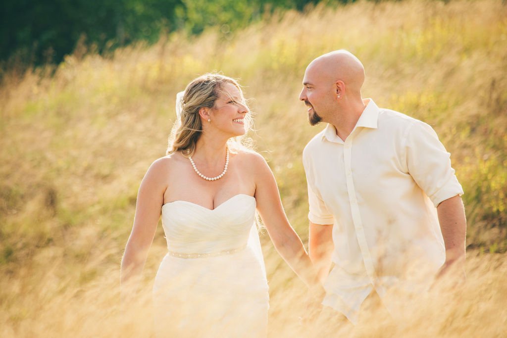 A bride and groom holding hands and smiling at each other during their elopement at Owl's Nest in New Hampshire. Elopement photography by Mike Indi.