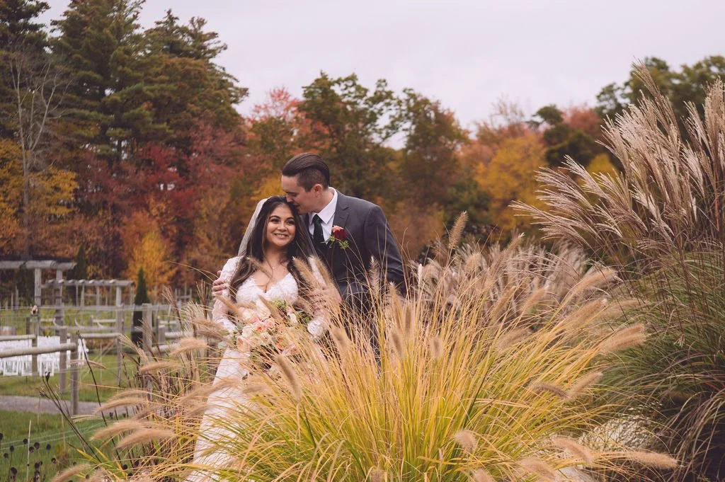 A stunning bride and groom surrounded by peak fall foliage on their wedding at Labelle Winery in Derry, NH. Wedding photography by Mike Indi.