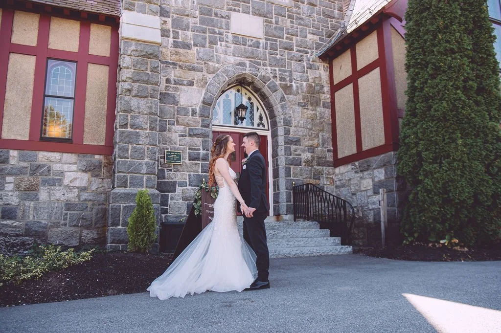 A bride and groom sharing a passionate embrace during their wedding at Searles Chapel in Windham, NH. Wedding photography by Mike Indi.