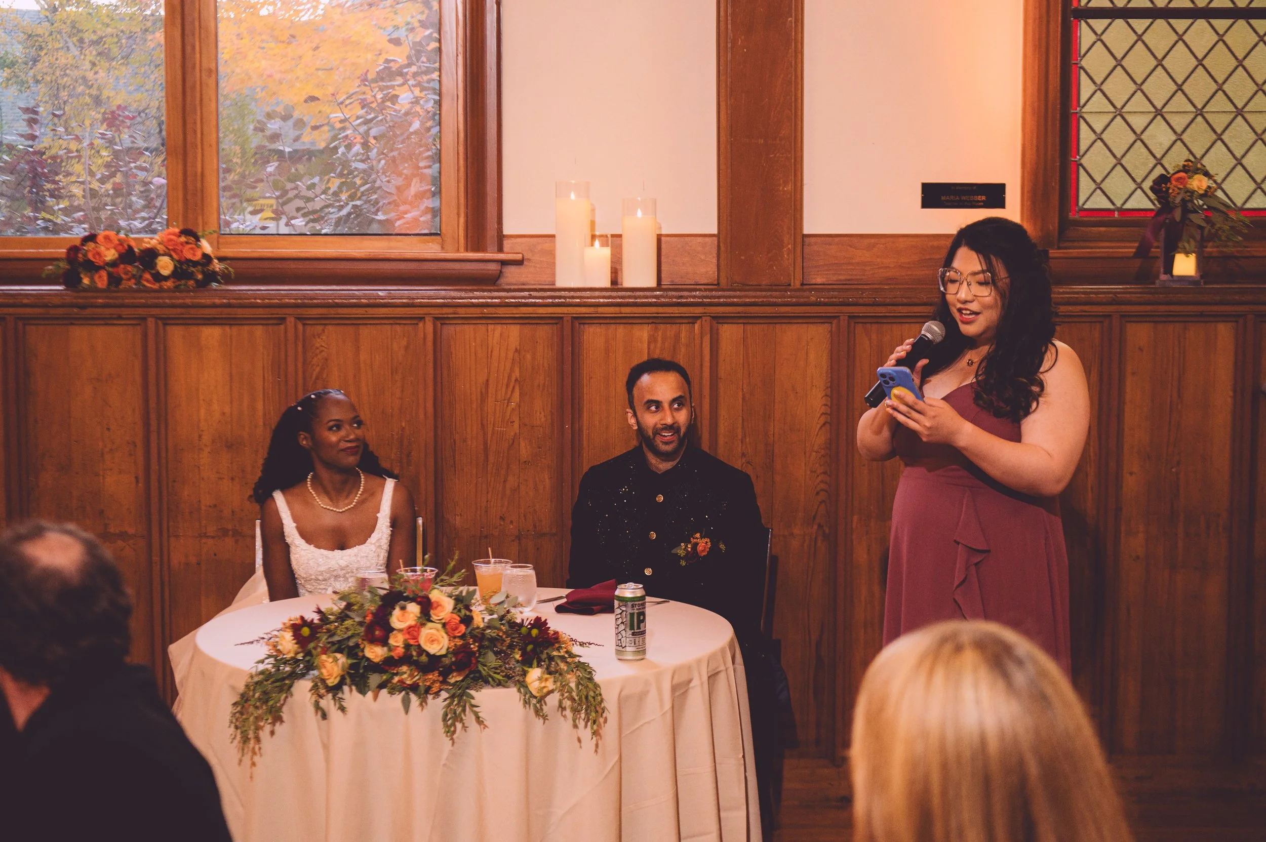 A bride and groom listening to the Maid of Honor recite her speech during their wedding reception at Searles Chapel in Windham, NH. Wedding photography by Mike Indi.