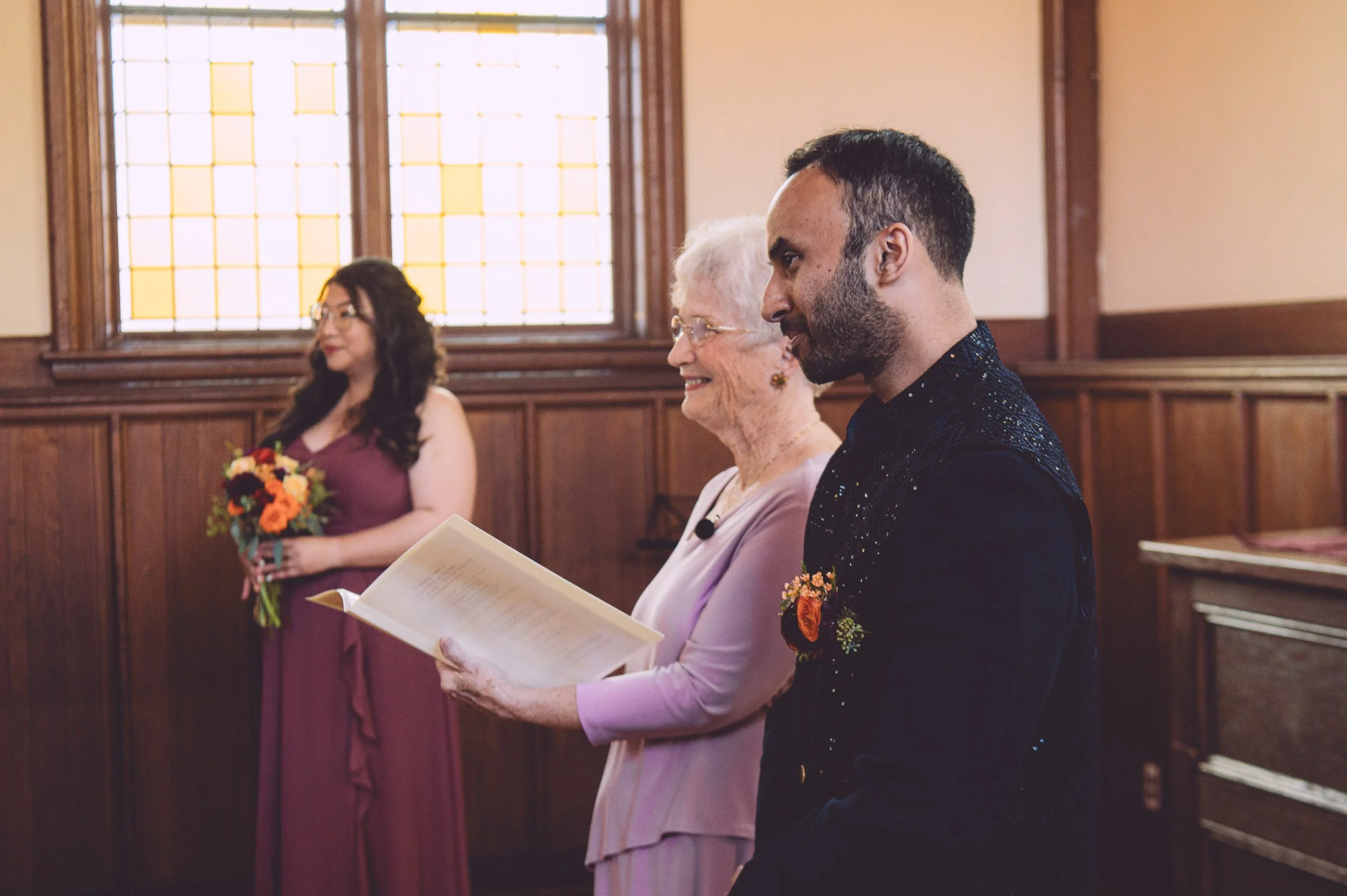 A loving groom watches his bride walking down the aisle during their wedding ceremony at Searles Chapel in Windham, NH. Wedding photography by Mike Indi.