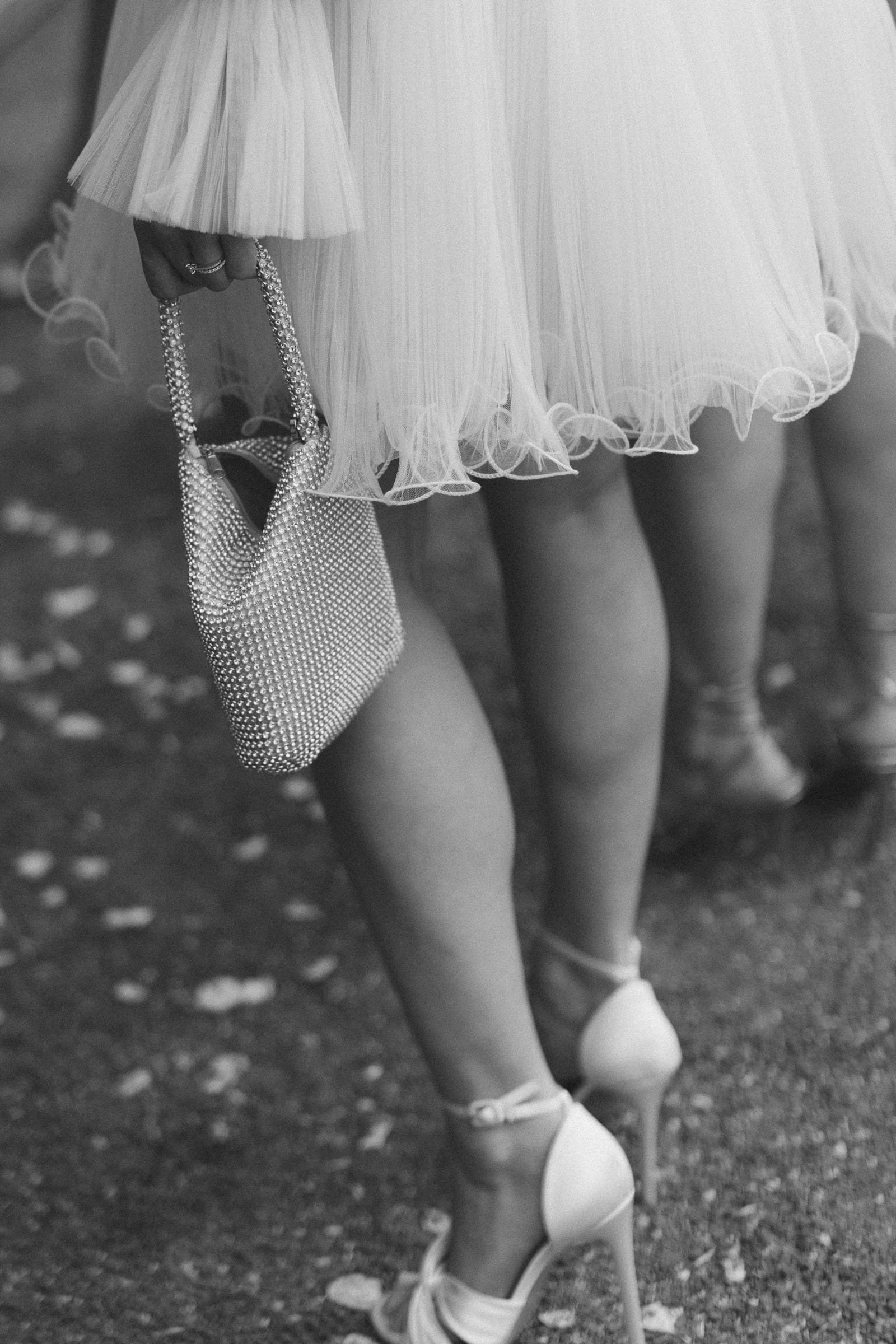 Frau in Tutu und High Heels trägt eine kleine, glitzernde Clutch.