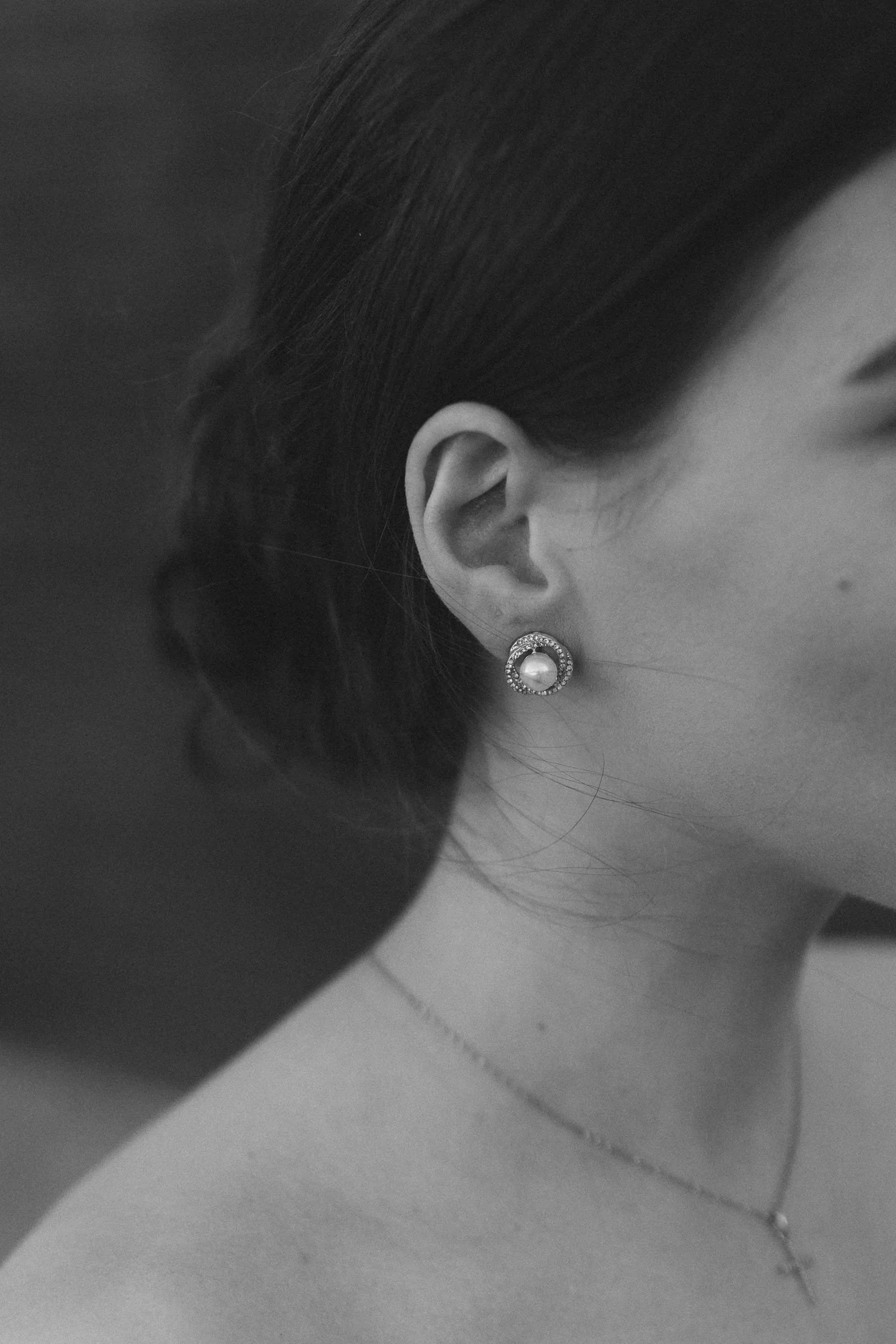 Nahaufnahme eines Frauenhufs mit einer Perlenkette und einem kreisförmigen Ohrring.