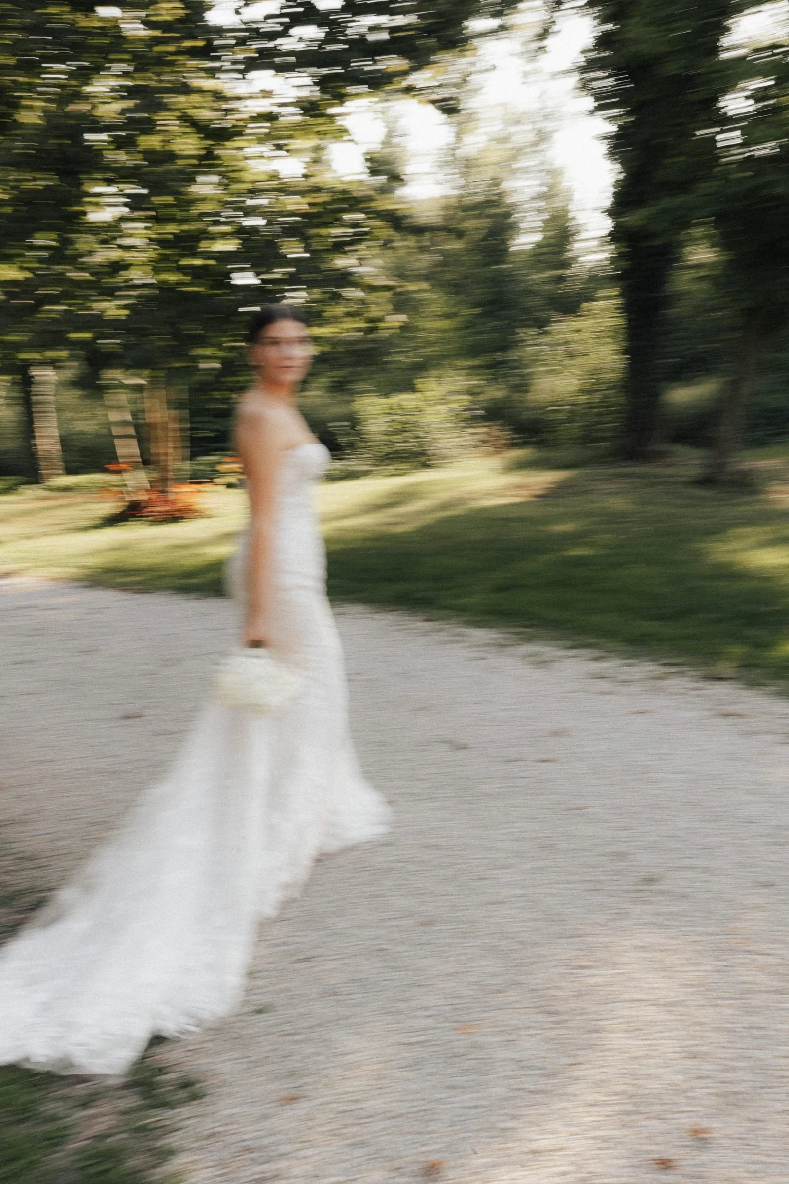 Ein unscharfes Foto einer Frau in einem weißen Brautkleid, die draußen auf einem Weg steht.